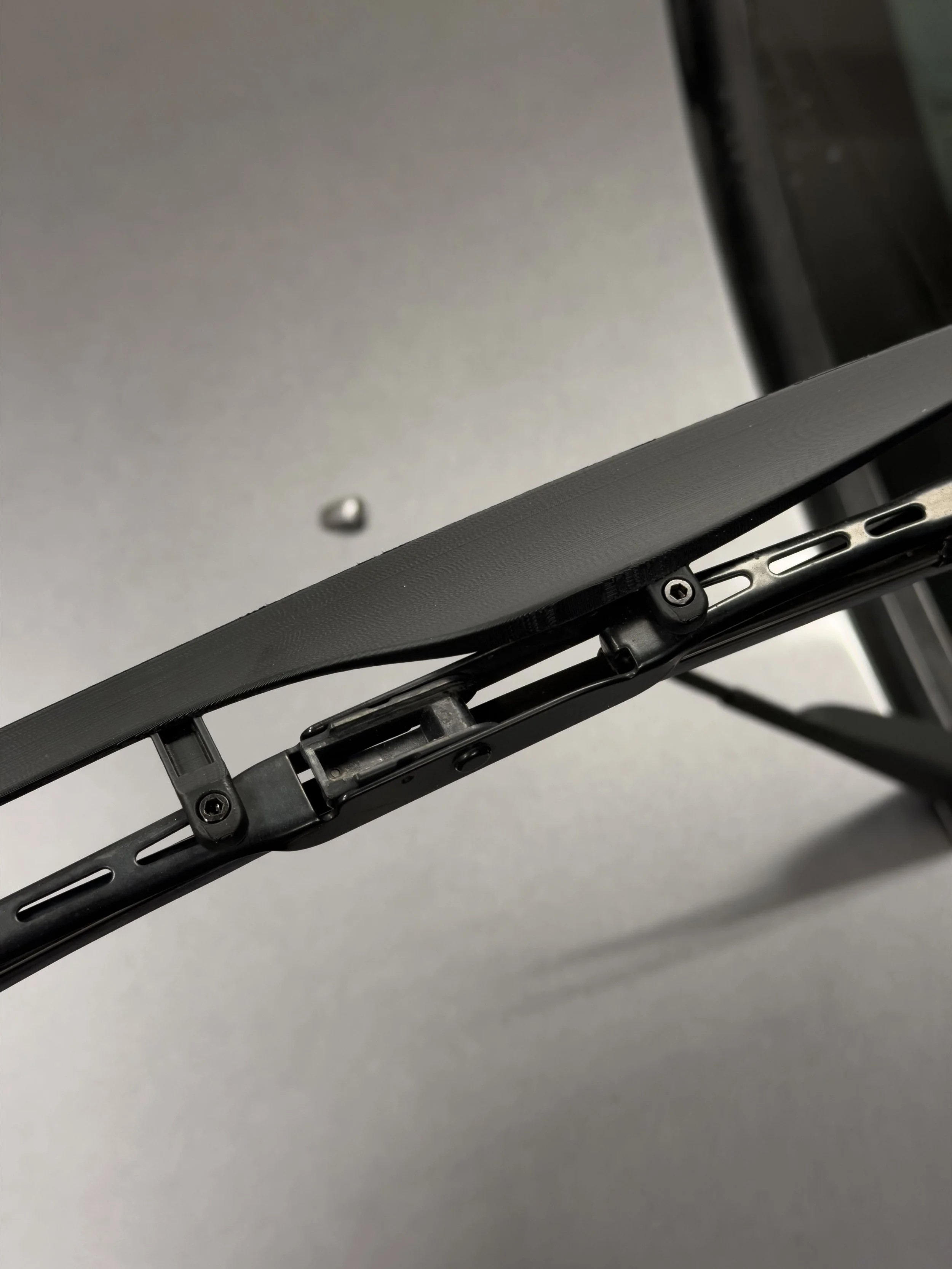 Close-up of a black bicycle saddle from below, showing the mounting rail and screws.