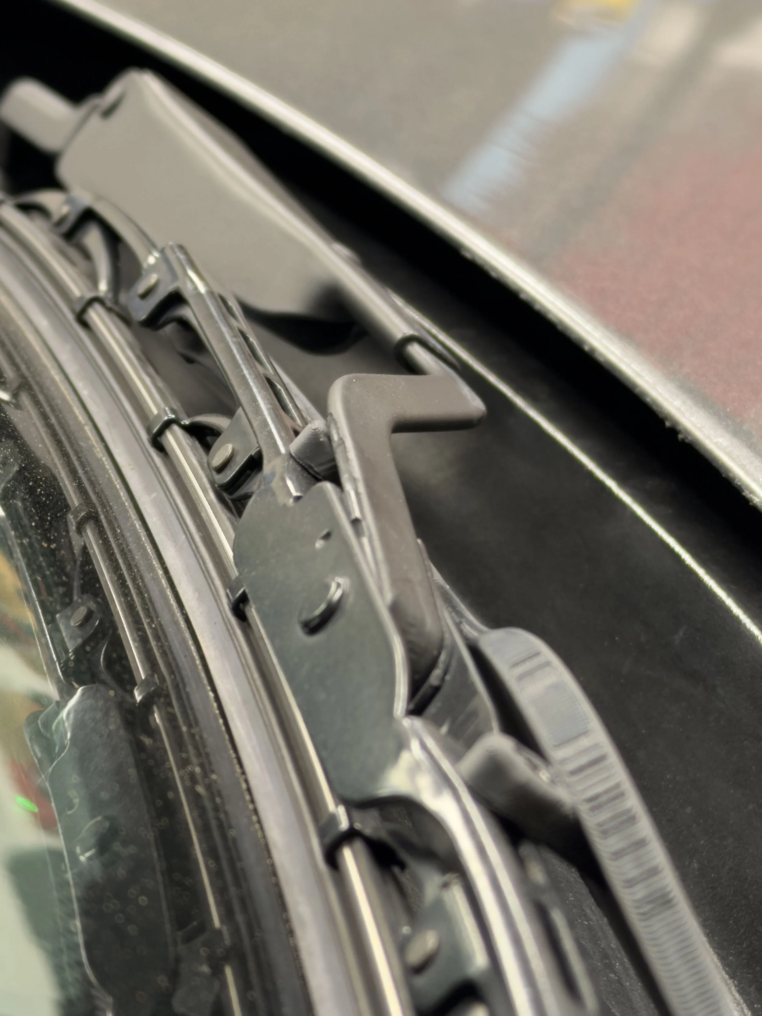 	
Close-up of a vehicle's windshield wiper mechanism and metal frame.