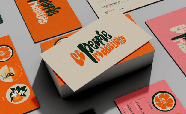 Stack of business cards with orange, cream, and pink backgrounds featuring various graphics and text including '99 People Franchising' and citrus fruit illustrations.