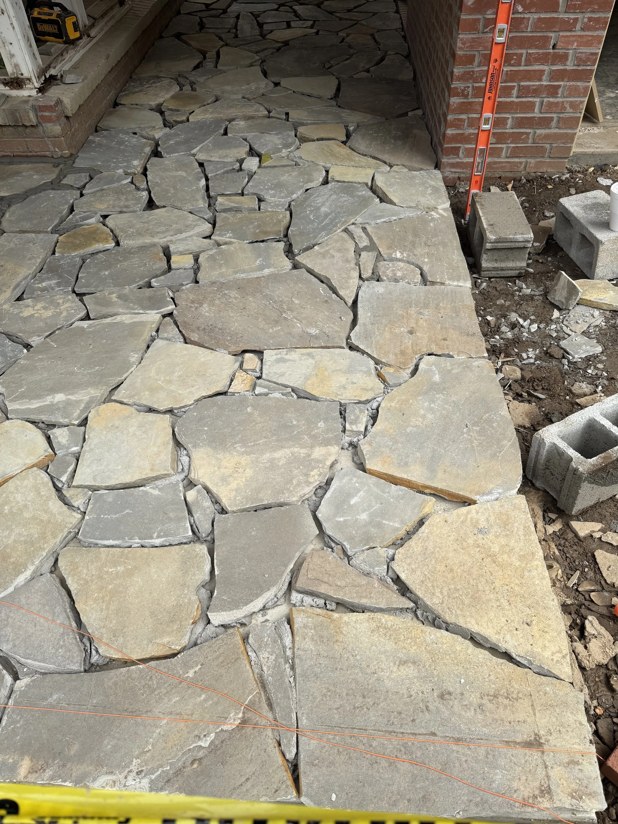 Unfinished stone path with irregular flagstones laid out outside a building under construction.