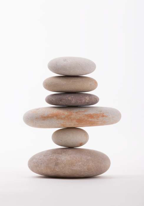 Stack of six smooth, flat stones in varying sizes and colors against a white background