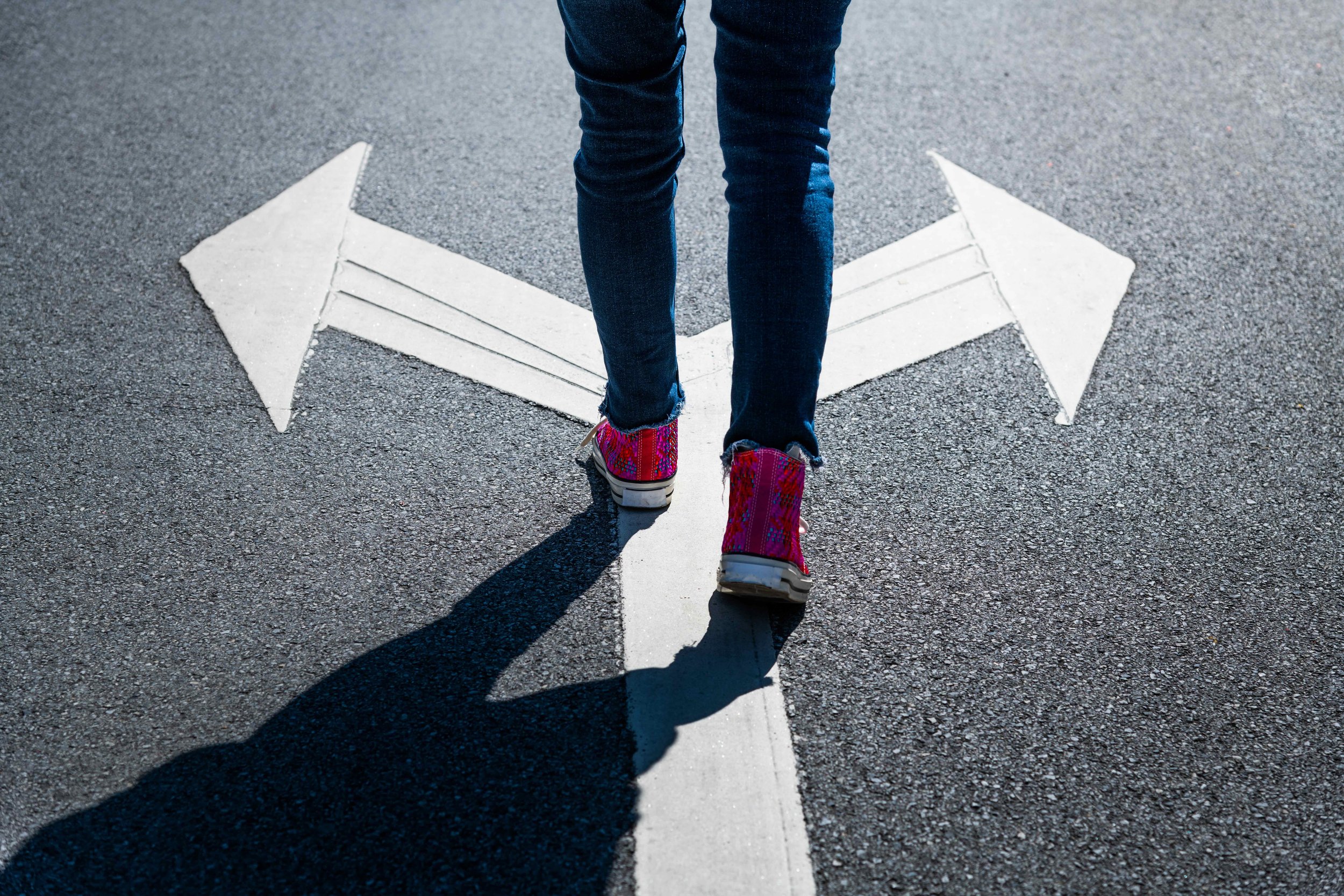 Teen walking on a street with arrows pointing left and right