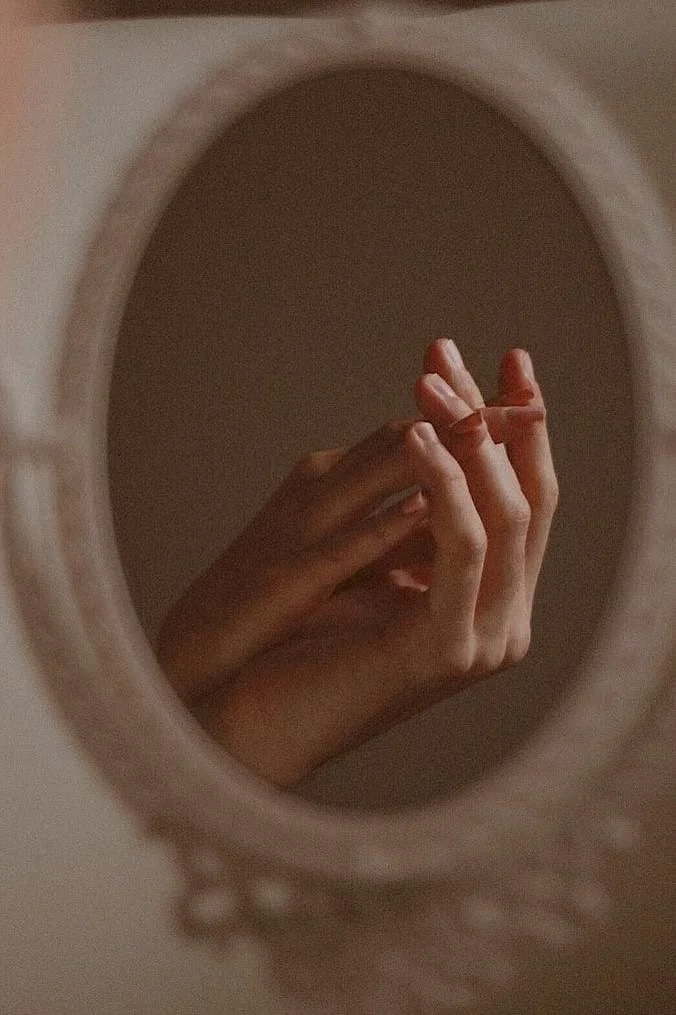 Esthetician hands, reflected in a round mirror, intentional touch at LUMÉ skin in Old Town, Alexandria.