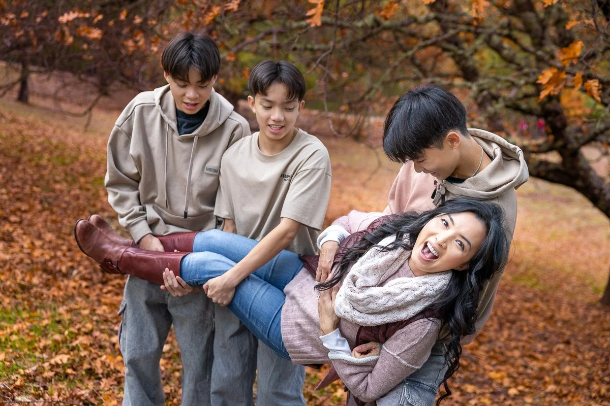 Bay Area outdoor family photography session with teenage sons carrying their mother through autumn oak leaves