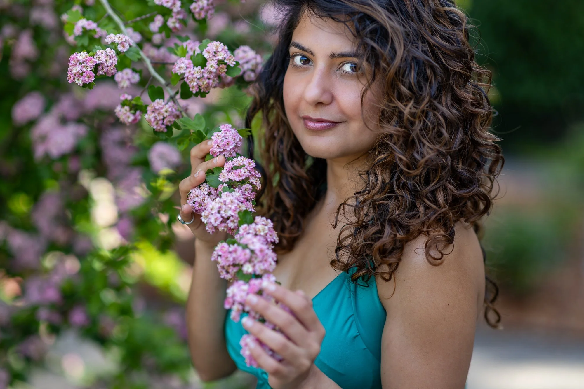 Woman holding pink spring blossom branch and looking at camera, Filoli garden portrait session, natural light