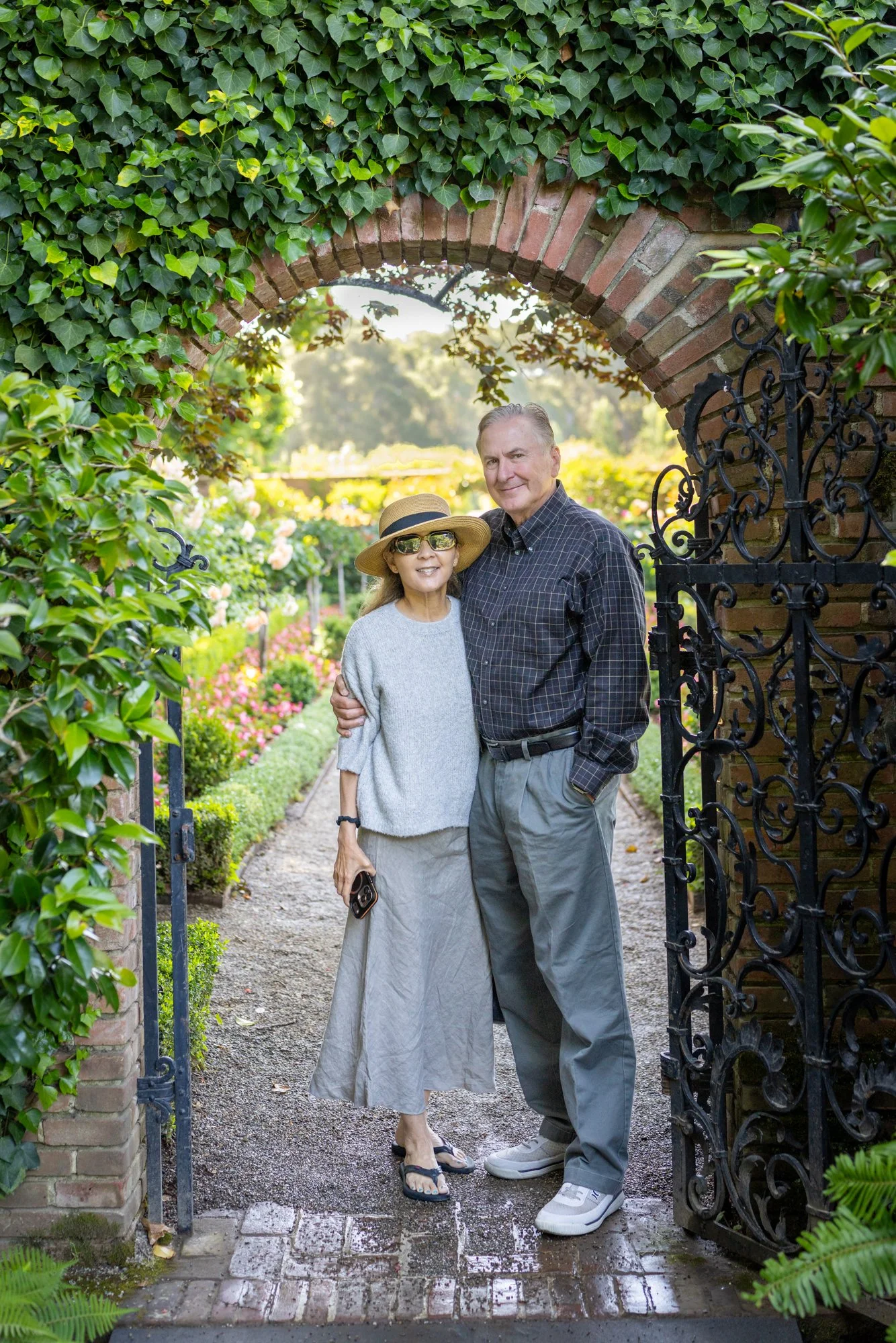 Couple under an ivy brick arch at Filoli with the rose garden glowing behind, natural light, Woodside