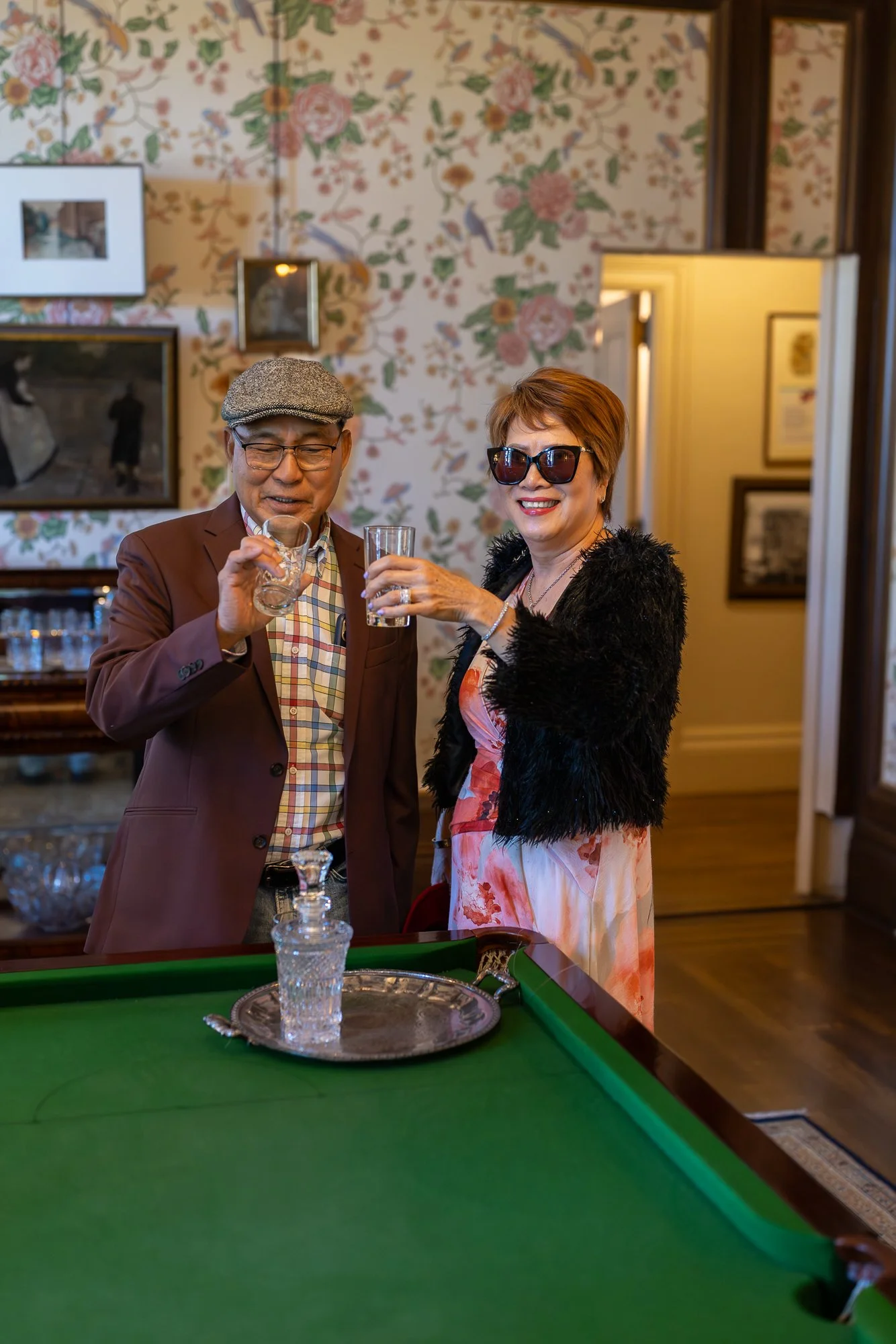 Older couple raising a toast in Filoli Billiards Room, chinoiserie wallpaper, Bay Area spring portrait