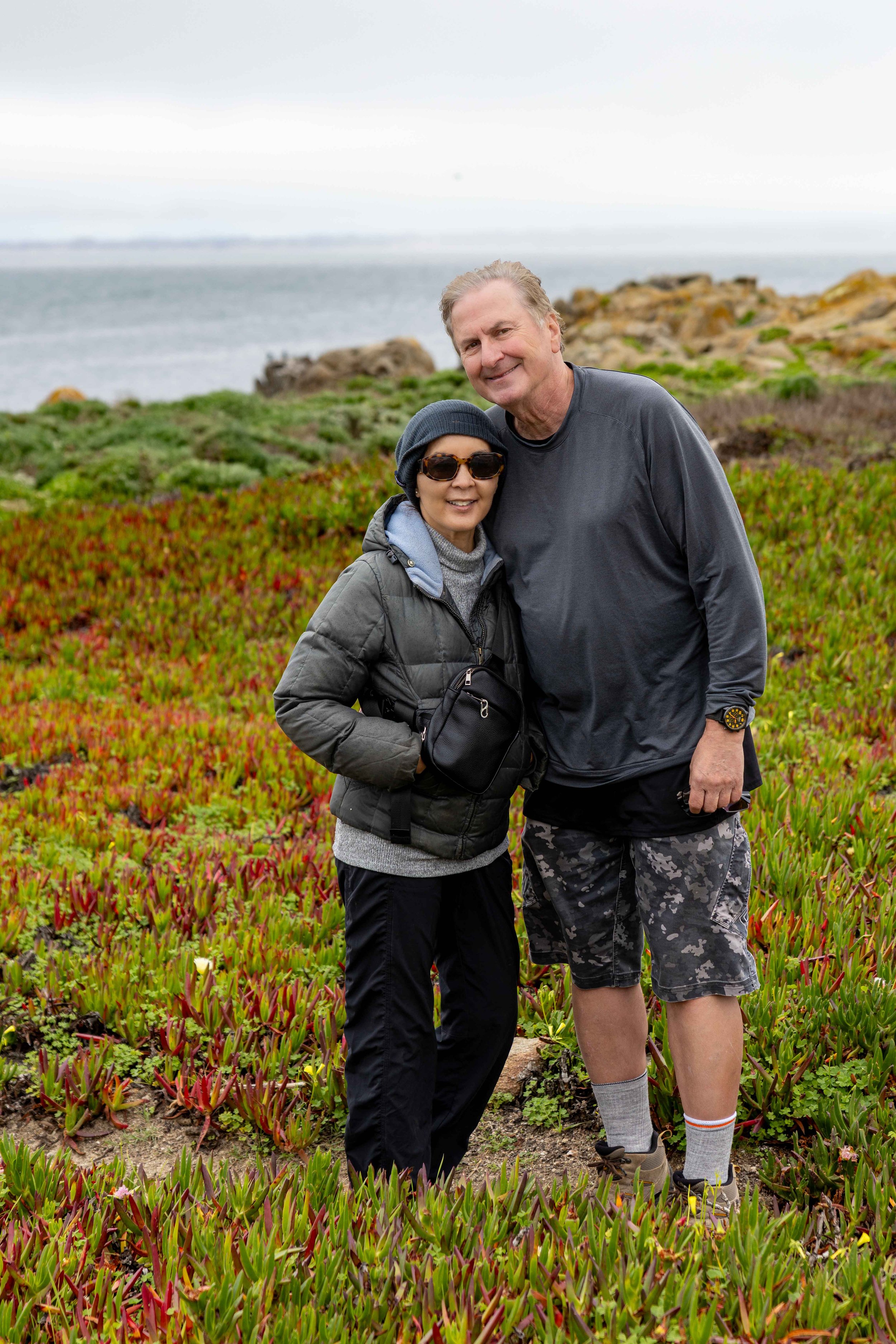 Standing in a carpet of blooming ice plant with the Pacific stretching to the horizon — spring cycling adventure photography session on the Monterey Peninsula coastline.