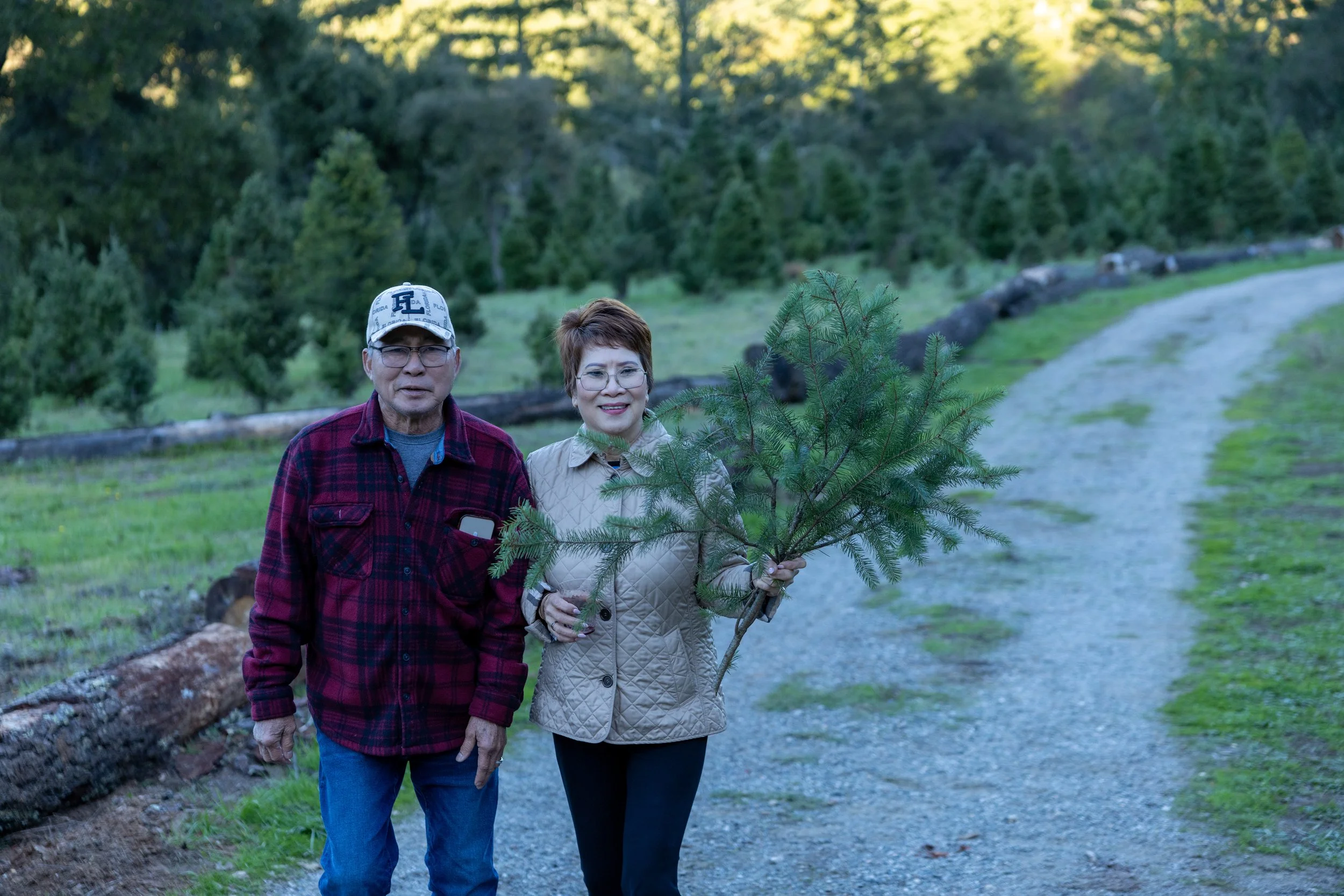 people holding evergreen branch on gravel path in natural setting
