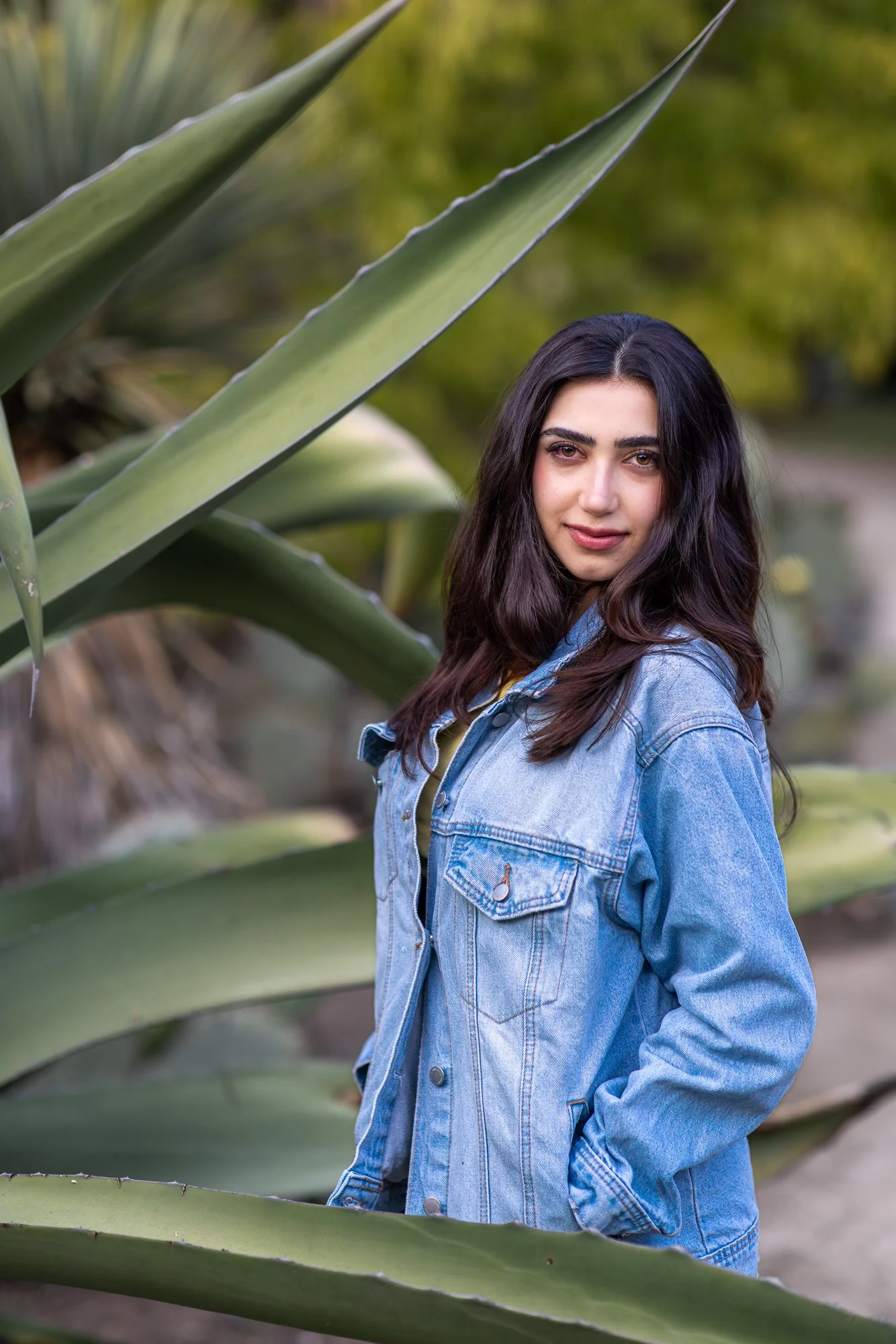 Close portrait of woman framed by large agave plant blades at Stanford Cactus Garden, natural light personal lifestyle photography Bay Area