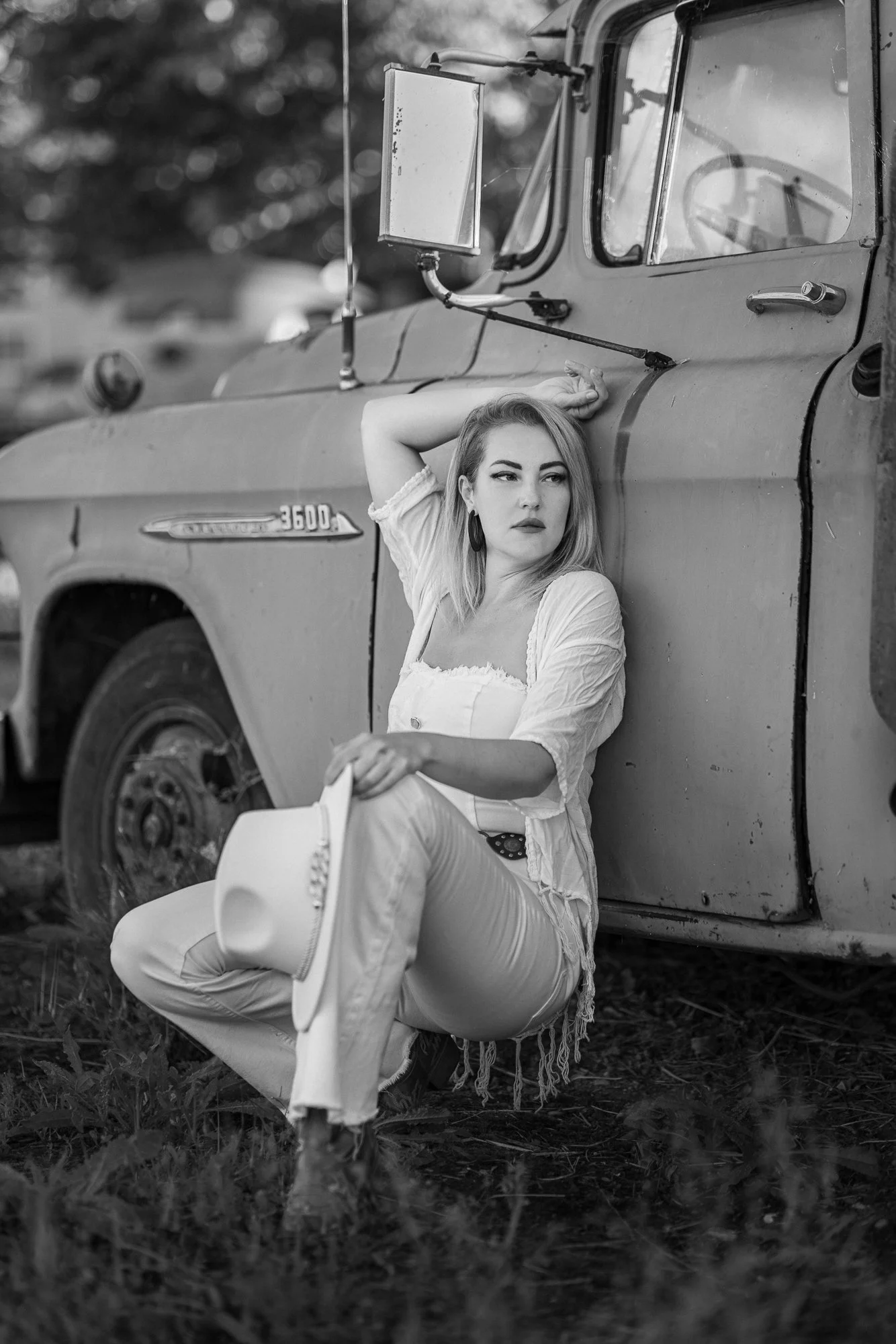 Woman in white Western outfit beside oxidised rust-patina vintage car at Niles Flying A property, Fremont CA