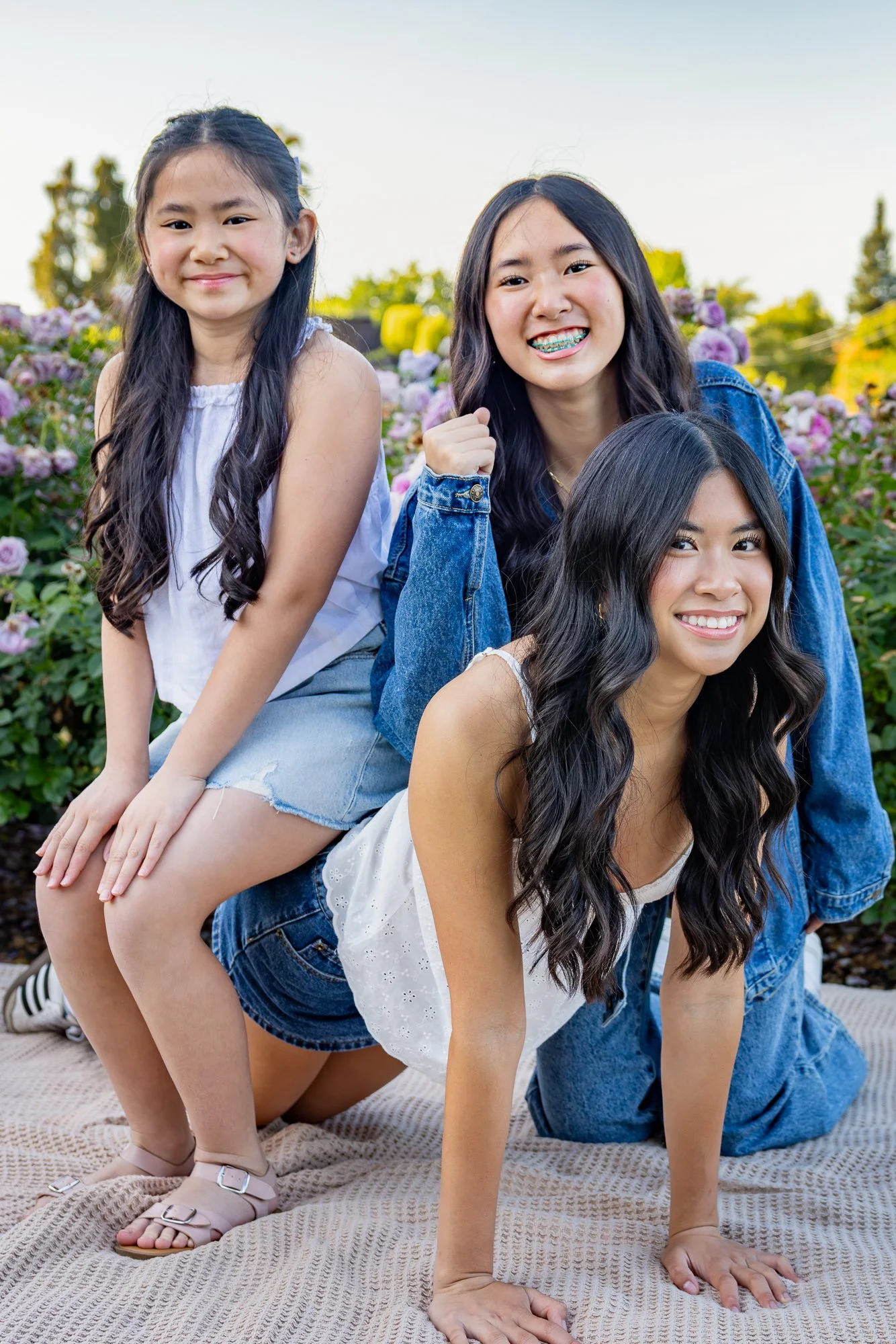 Three sisters posing together in a Bay Area rose garden during a family portrait session