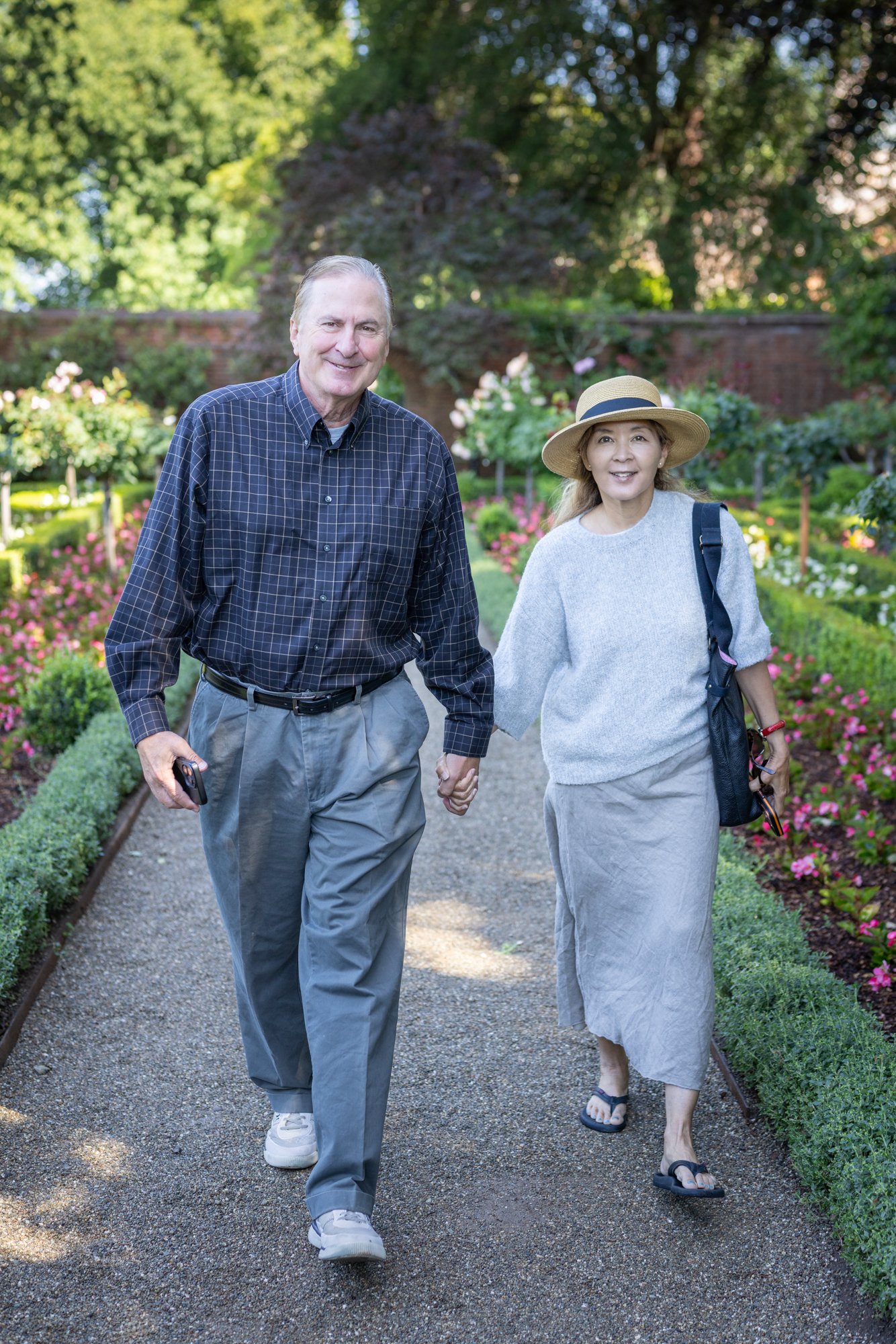 Couple walking hand in hand on a gravel rose garden path at Filoli, candid natural light, Woodside