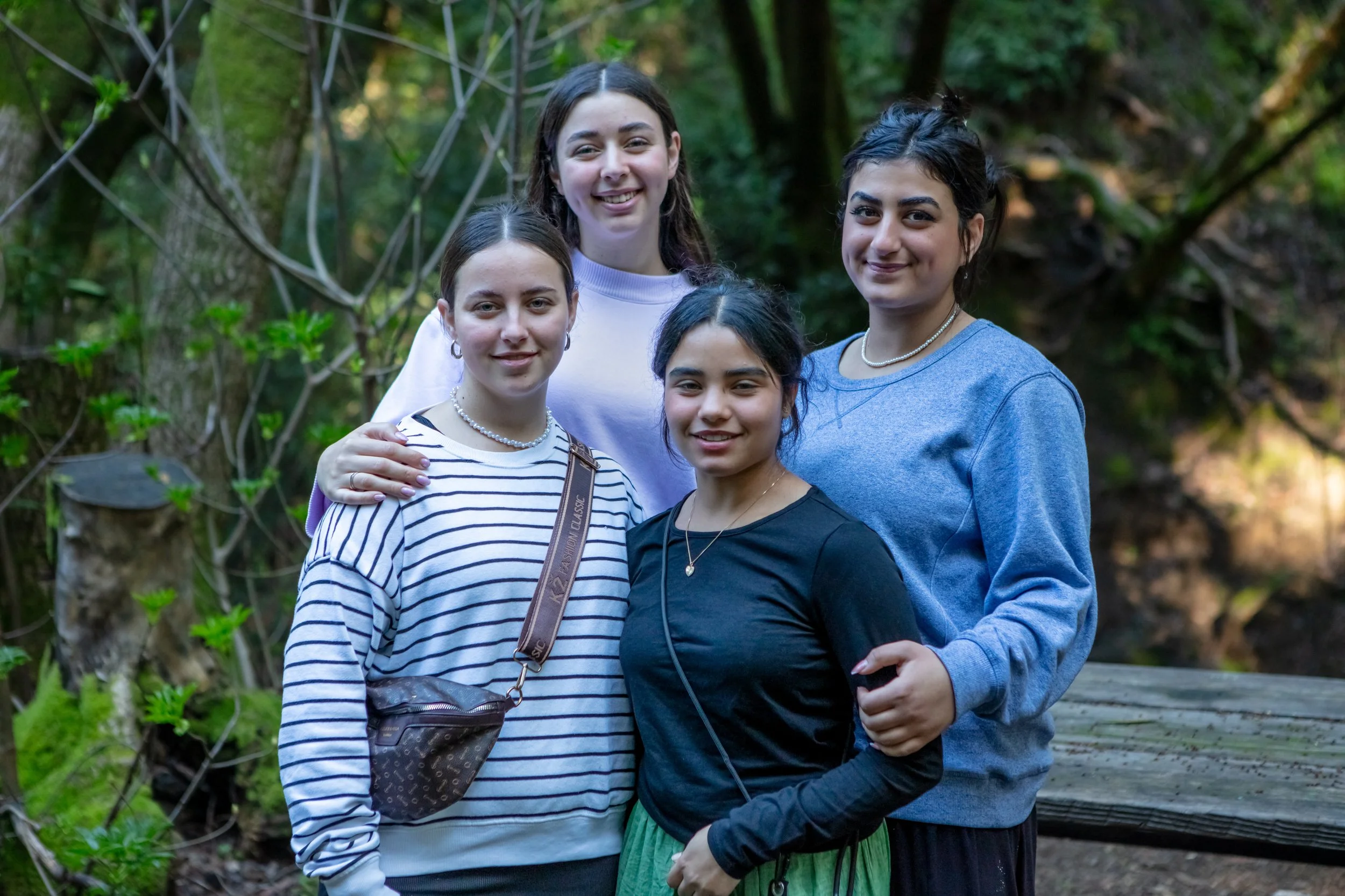 Hidden Villa Los Altos Family Photography Session - Four young women standing close together outdoors in a wooded area, smiling at the camera.