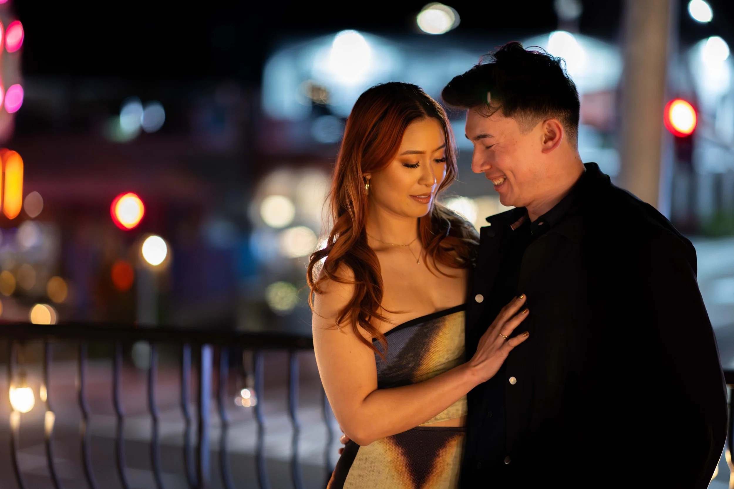 Romantic couple photography in Bay Area San Jose romantic moment between a man and a woman at night, with city lights and blurred background.