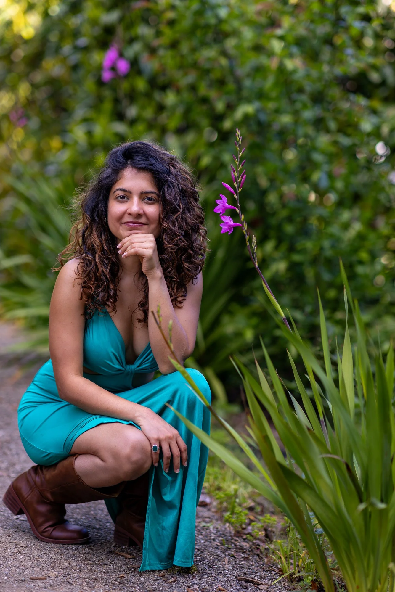Woman in teal dress crouching beside purple gladiolus flower at Filoli garden, Bay Area personal lifestyle photography