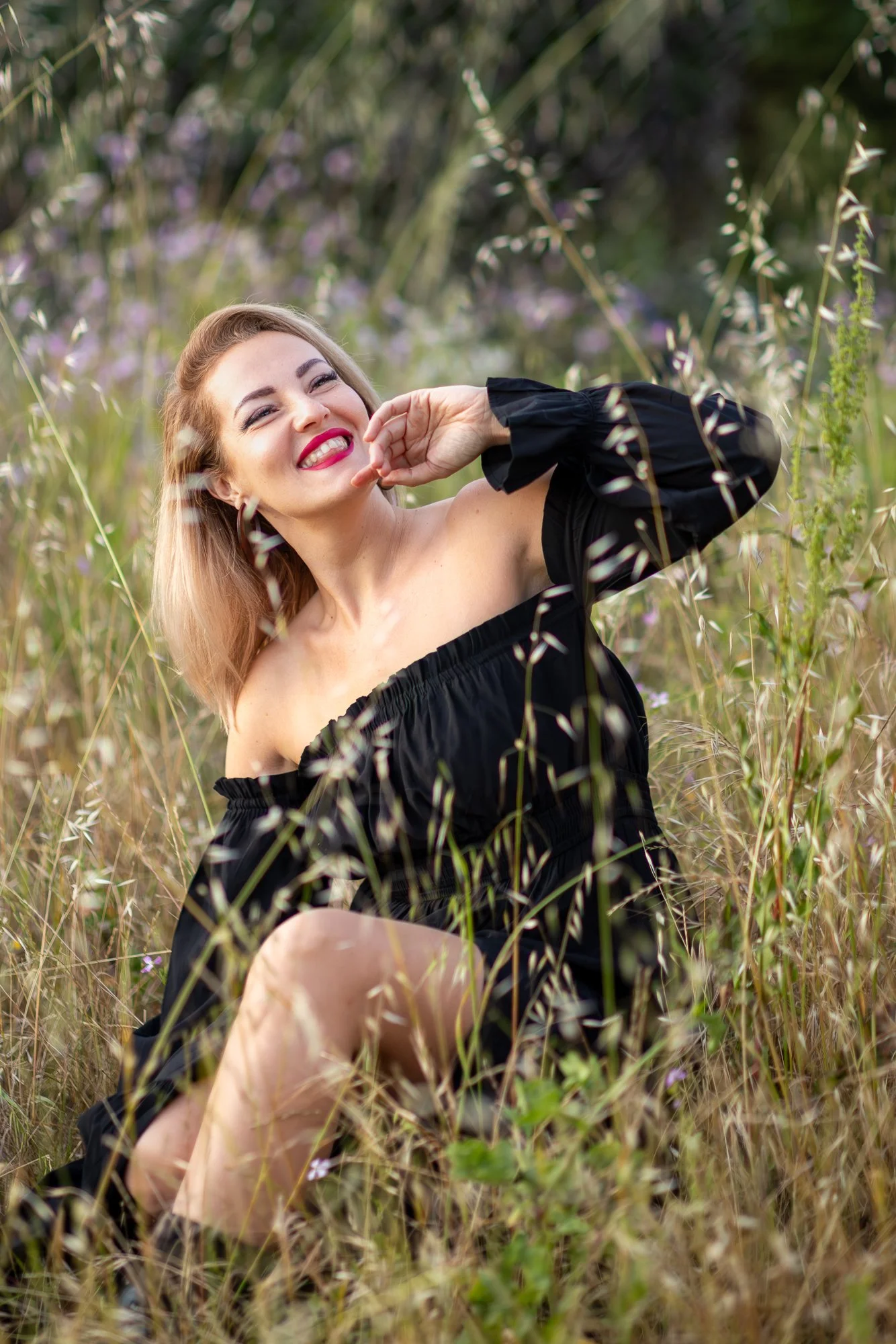 Woman in black off-shoulder dress sitting in dry oat grass and purple wildflowers at golden hour, Niles Fremont Bay Area