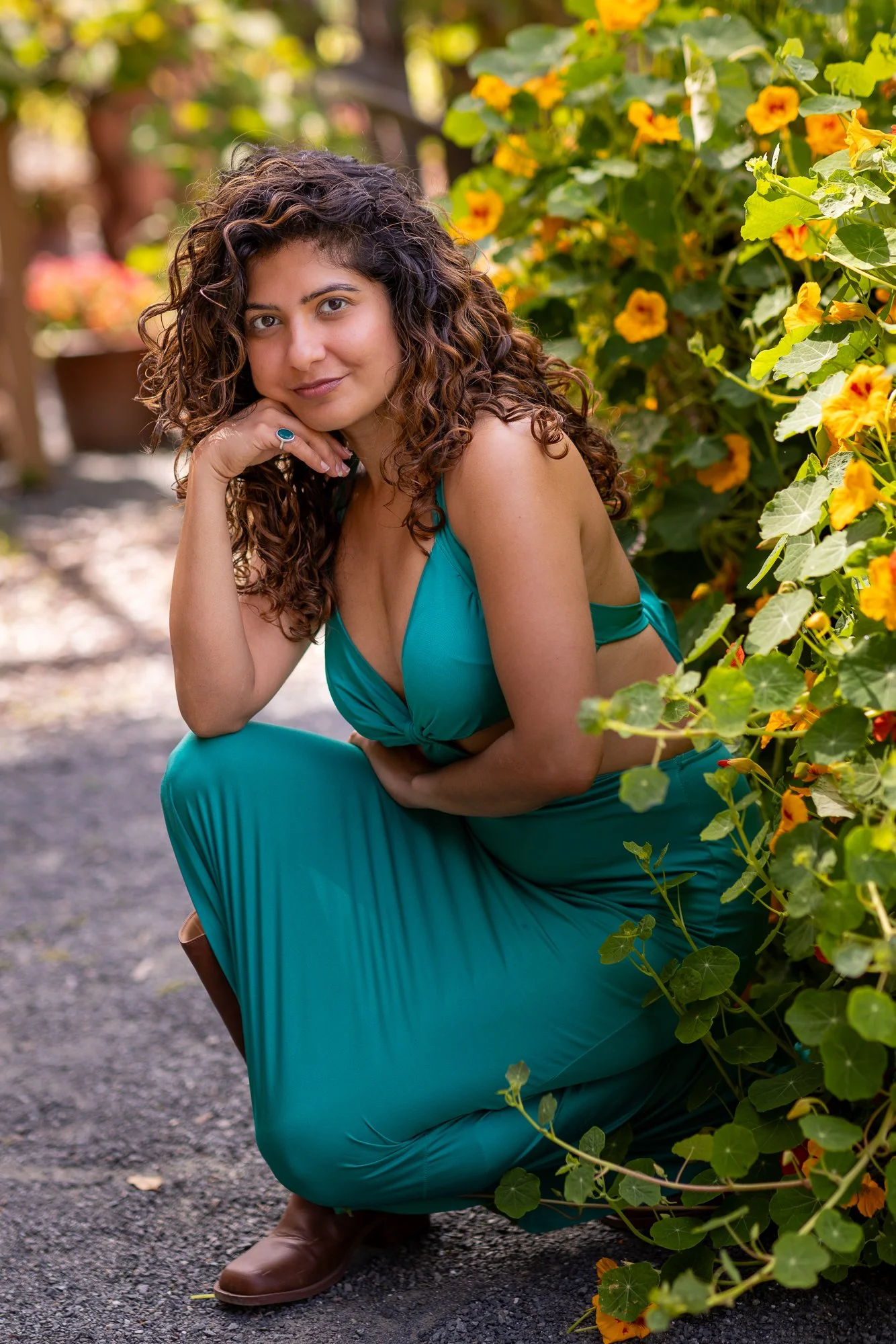 Woman in teal dress crouching beside orange nasturtiums on Filoli garden path, Peninsula lifestyle photography