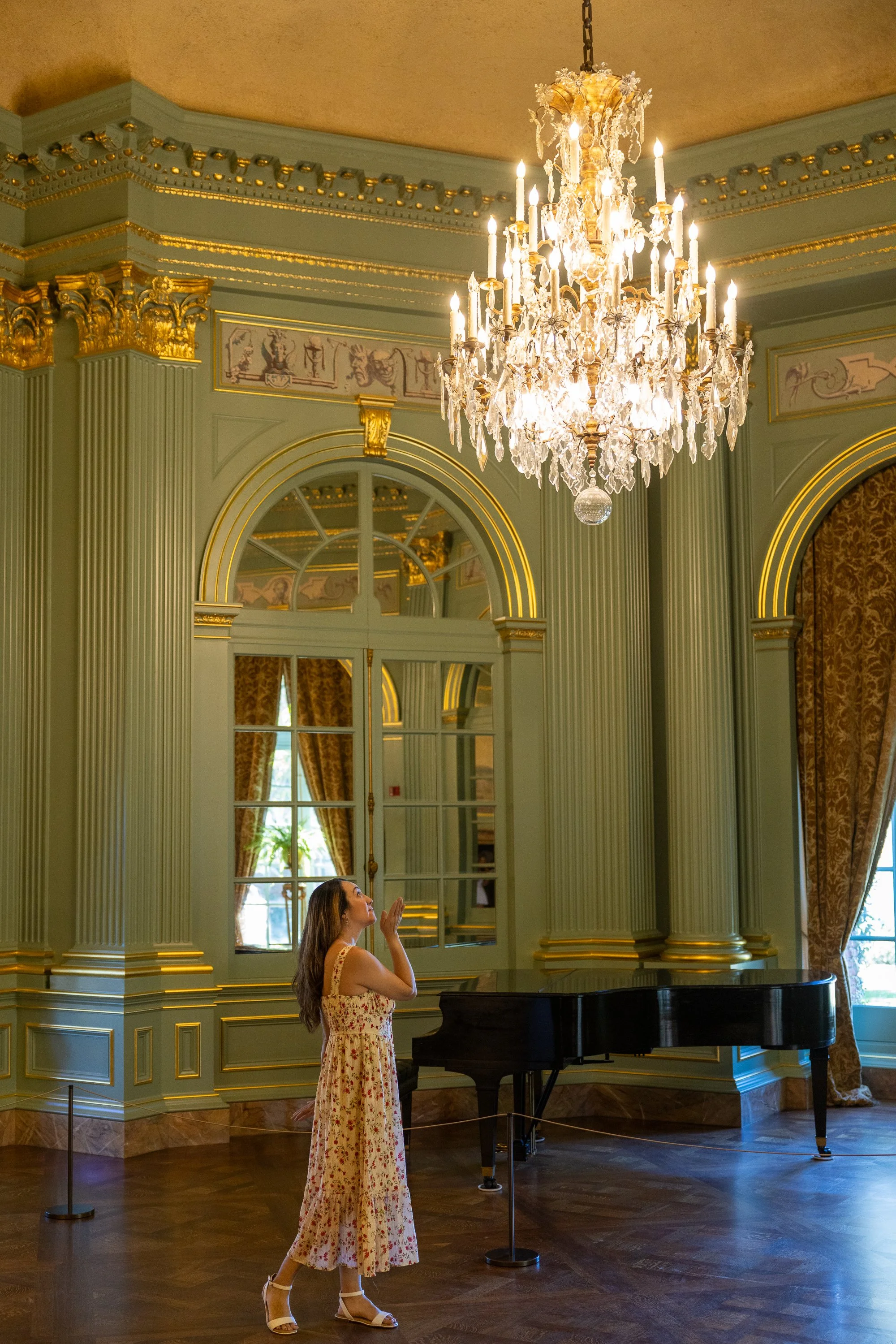 Woman in floral dress looking up at chandelier in Filoli ballroom
