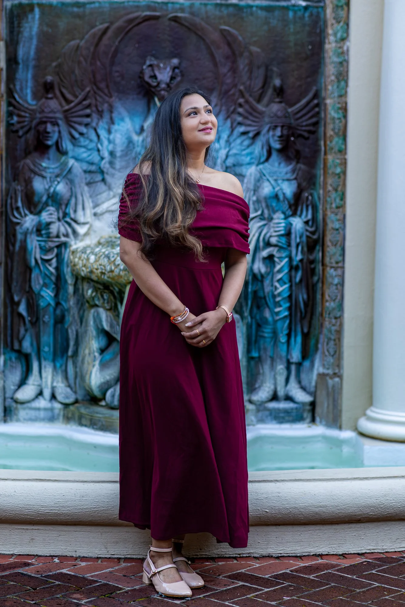 Woman in burgundy dress before bronze relief fountain sculpture at Villa Montalvo courtyard, Saratoga, personal lifestyle portrait