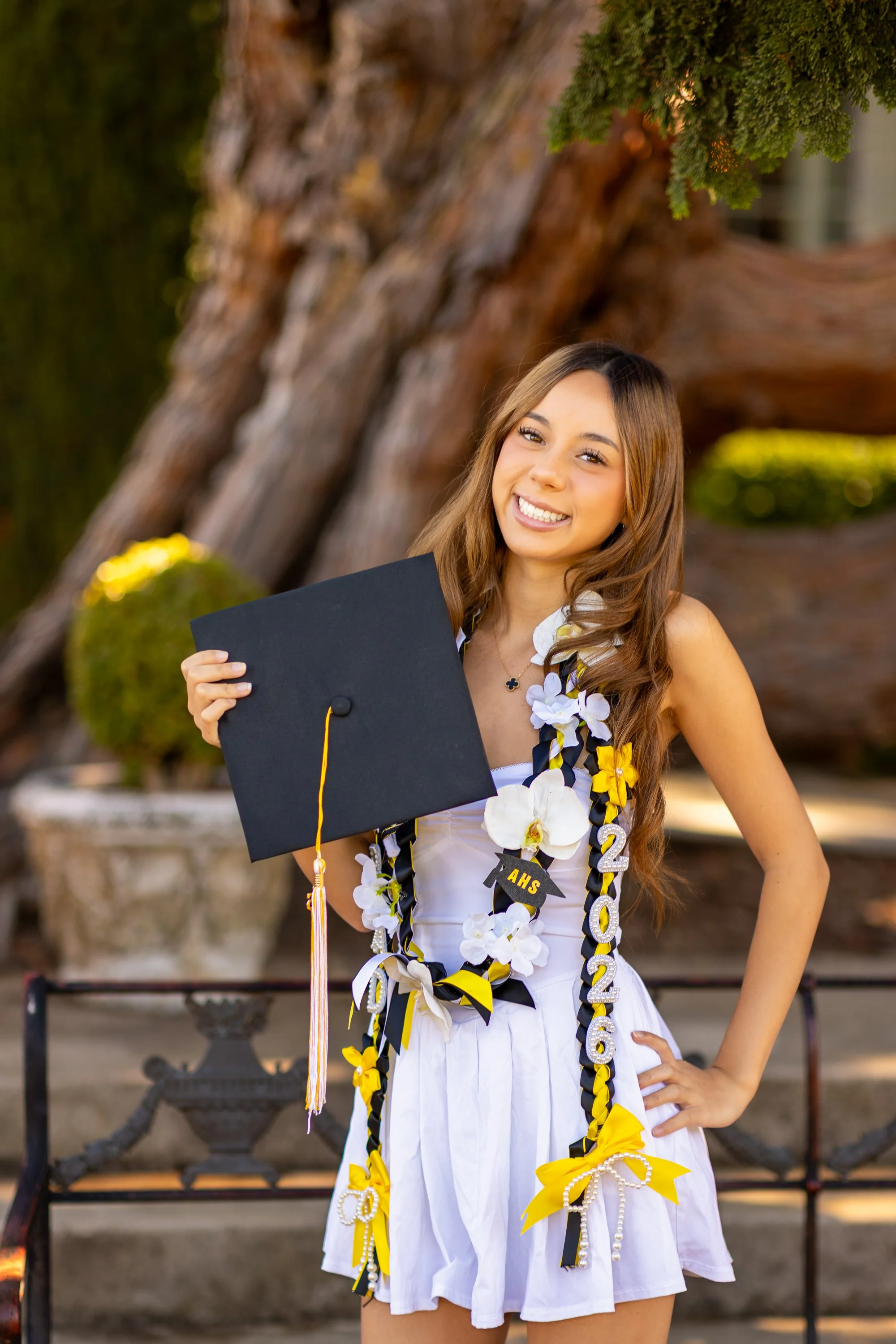 Graduate holding mortarboard cap with tassel, smiling, Filoli gardens Woodside