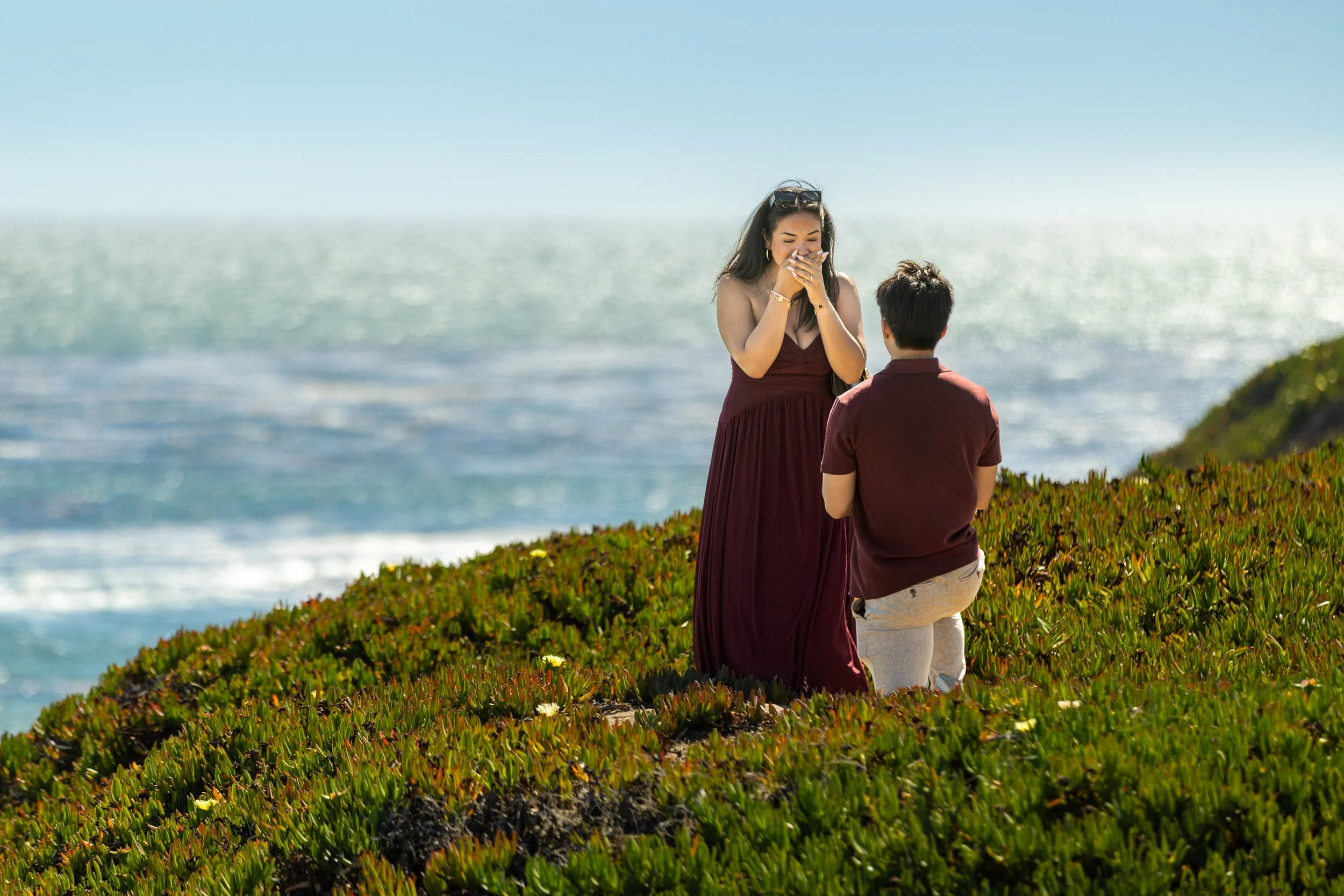 Woman covering her mouth in surprise during a proposal on West Cliff Drive, Santa Cruz