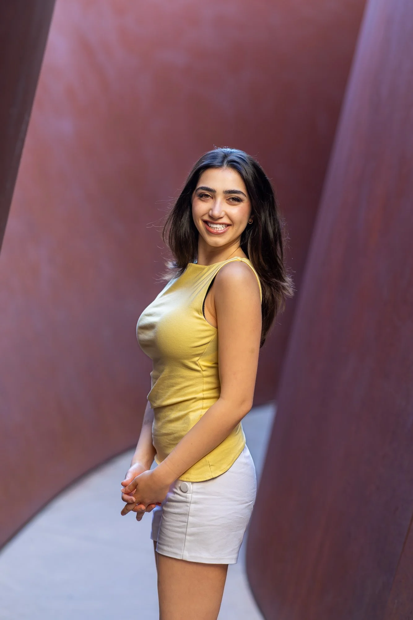 Woman laughing in profile between curved corten steel sculpture panels at Stanford Cantor Arts Center, candid natural light portrait