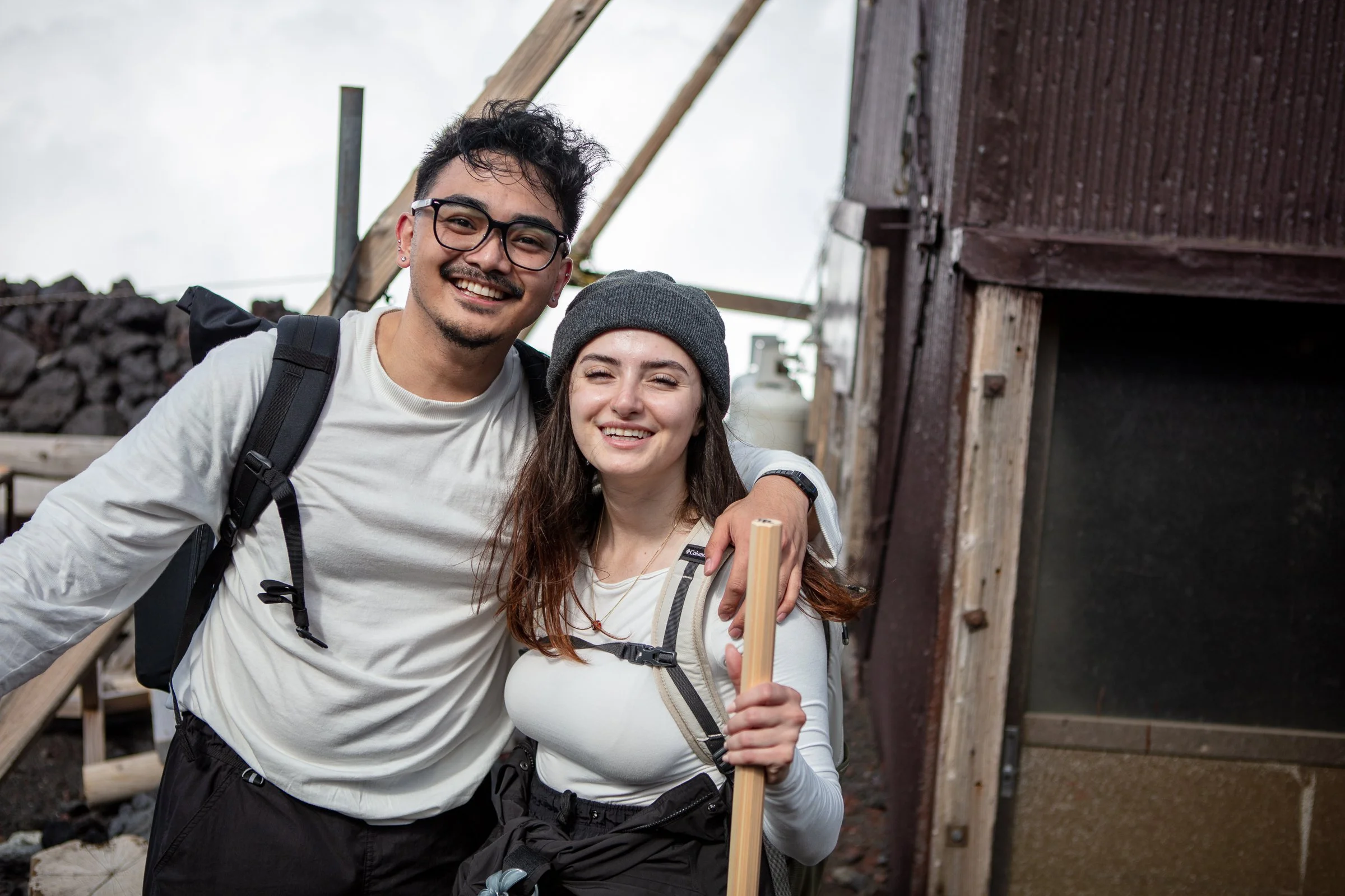 Couple smiling at Mt Fuji summit 3776m hiking poles Japan