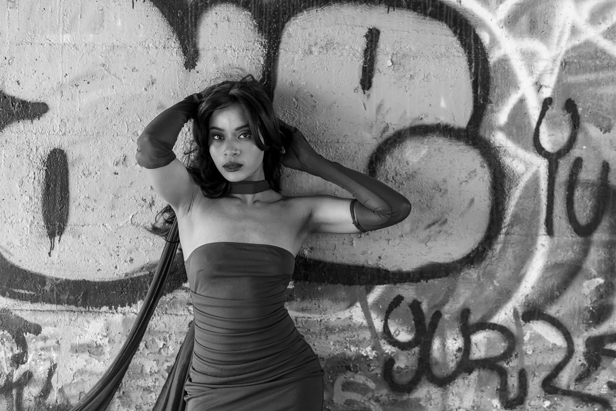 Black and white editorial portrait woman in red dress against graffiti concrete wall, Dumbarton Bridge Shoreline Trail Bay Area