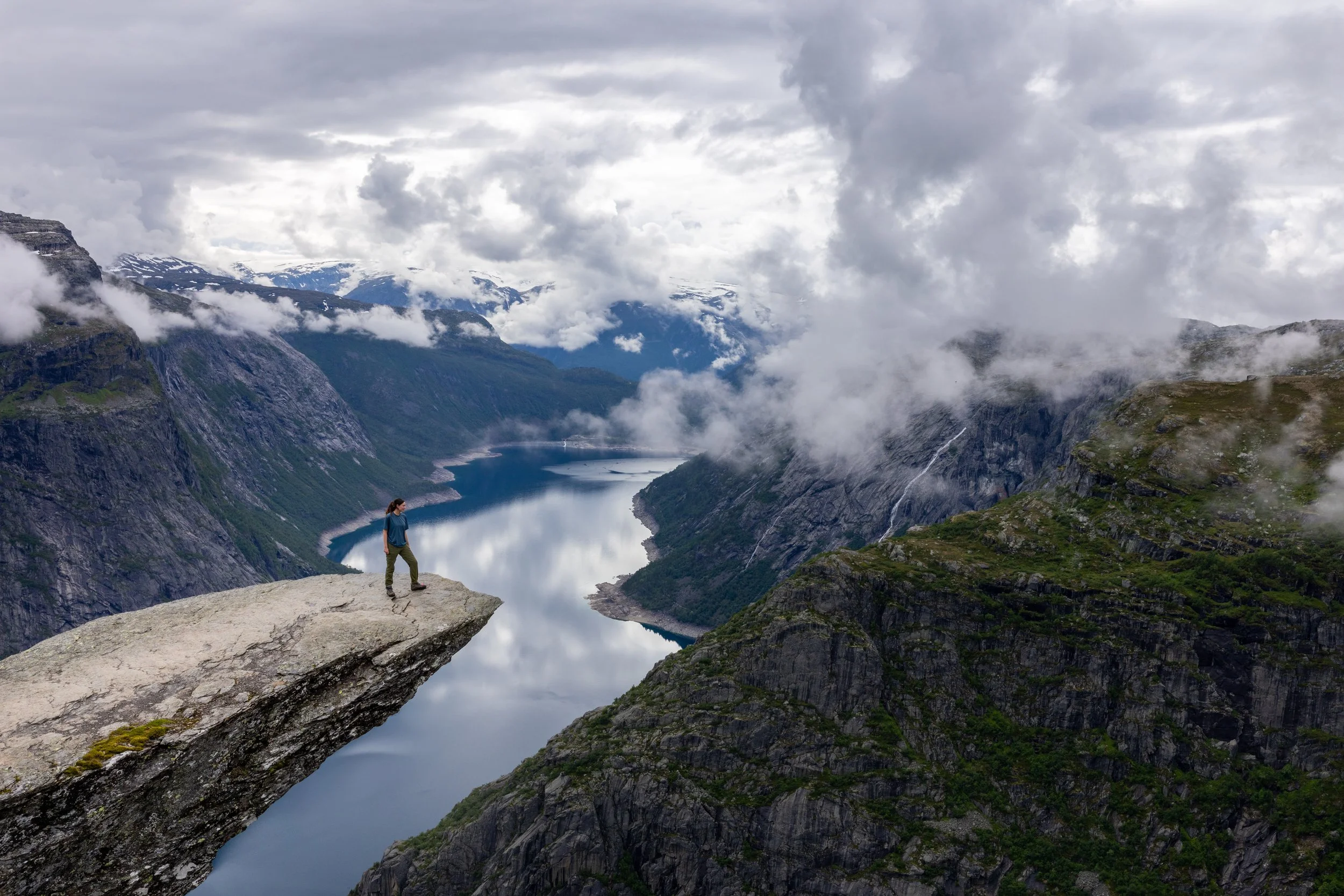 Trolltunga and fjord suddenly lit by a clear patch of sunlight after fog.