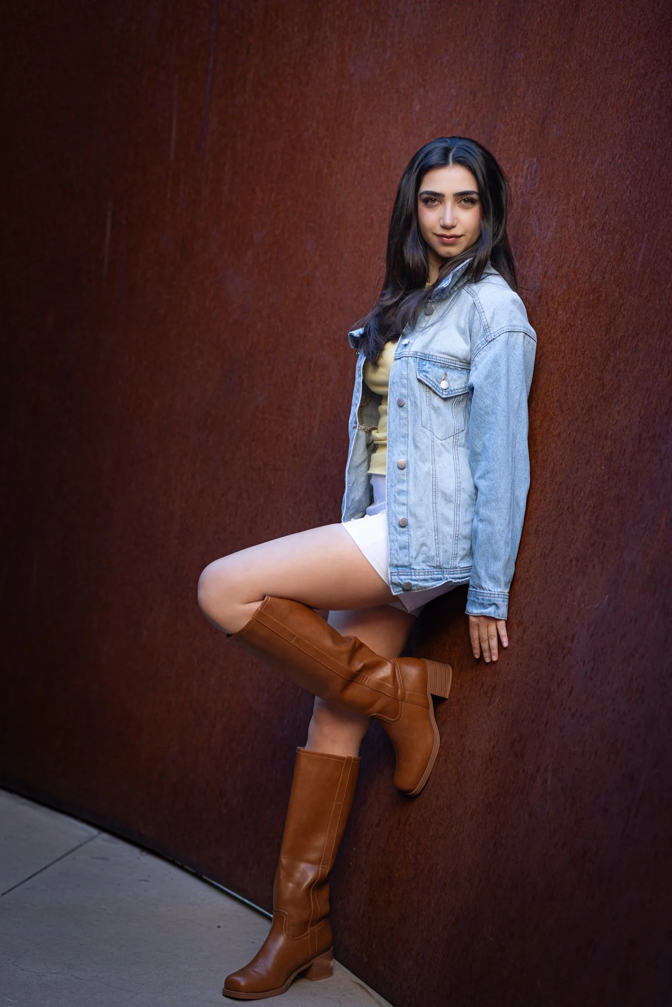 Woman in yellow top leaning against curved corten steel Richard Serra sculpture at Stanford Cantor Arts Center, editorial portrait
