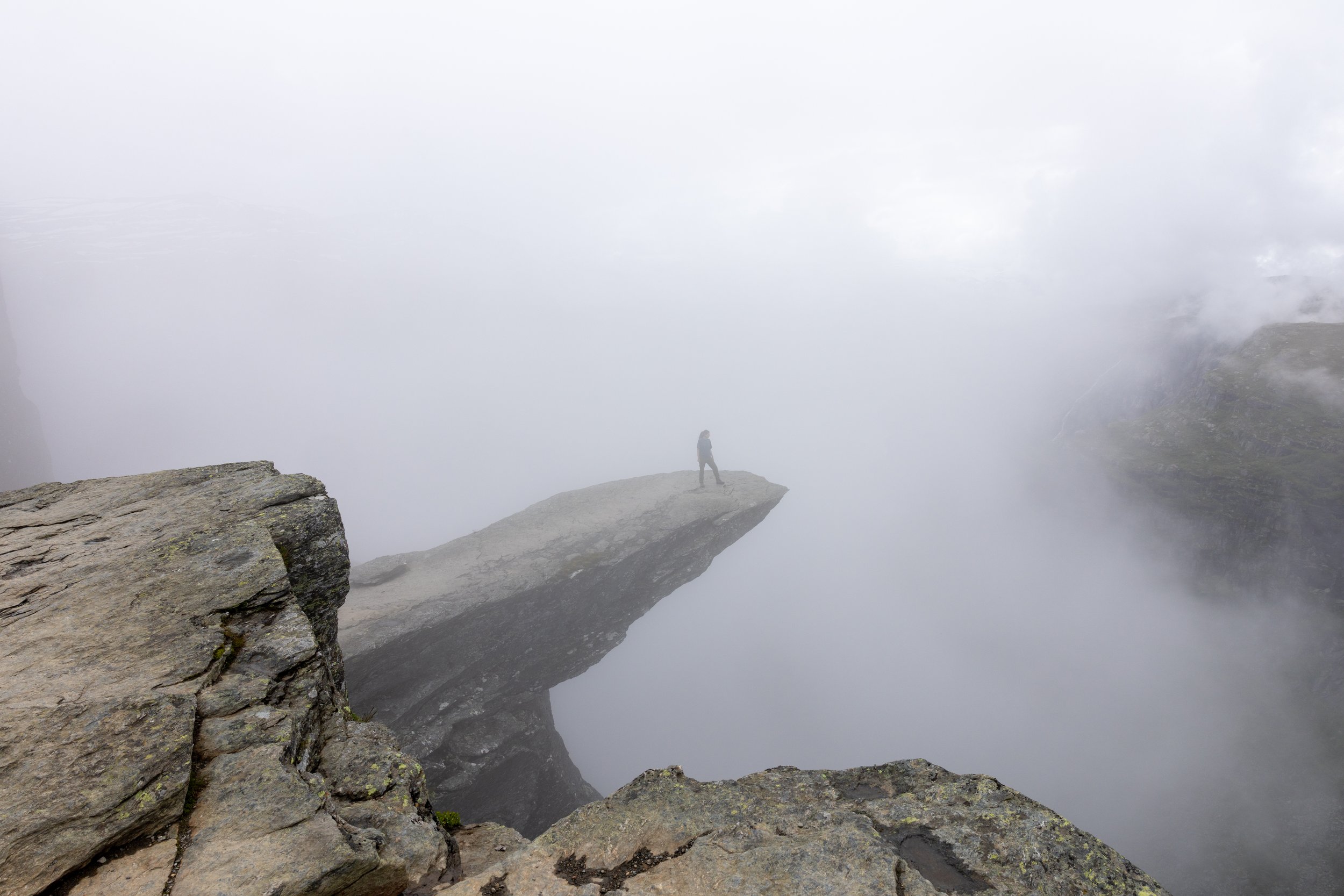 Trolltunga rock formation shrouded in low fog with muted background.