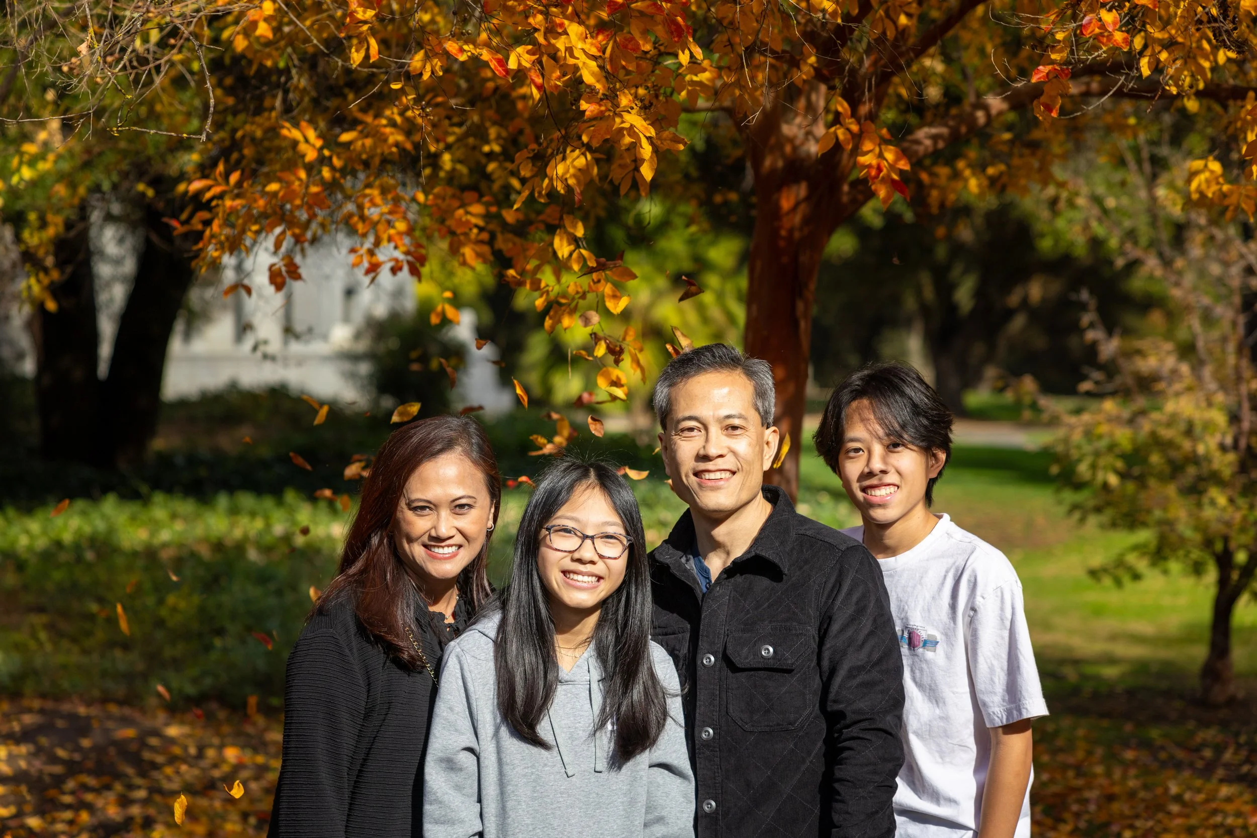 Bay Area family of four under bright autumn orange leaves during an outdoor family portrait session