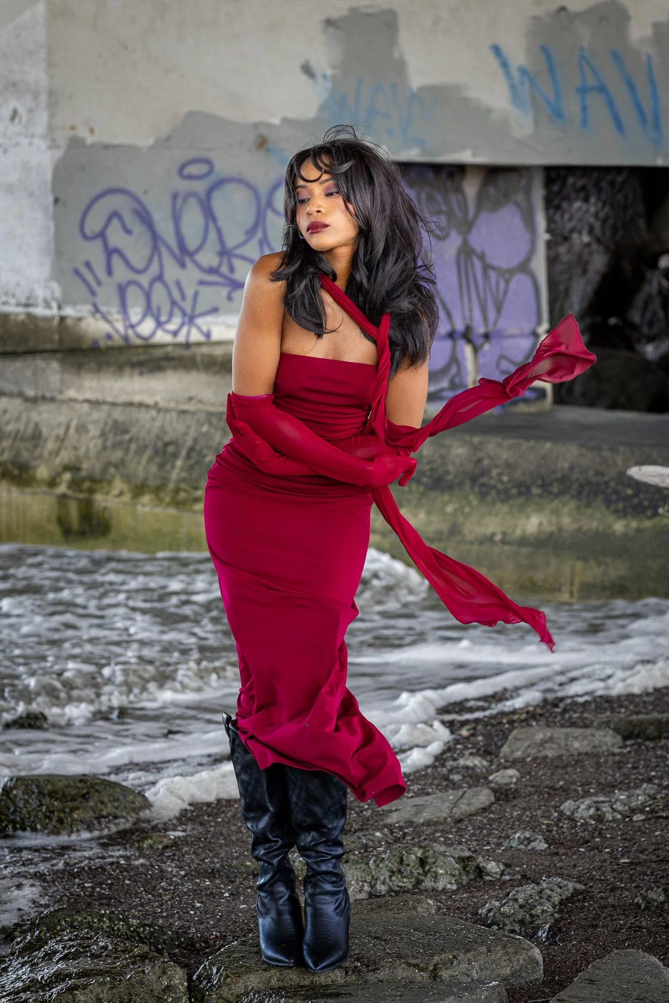 Woman in crimson gown at bay waterline, dress trailing in wind, graffiti concrete walls, Dumbarton Shoreline Trail Newark