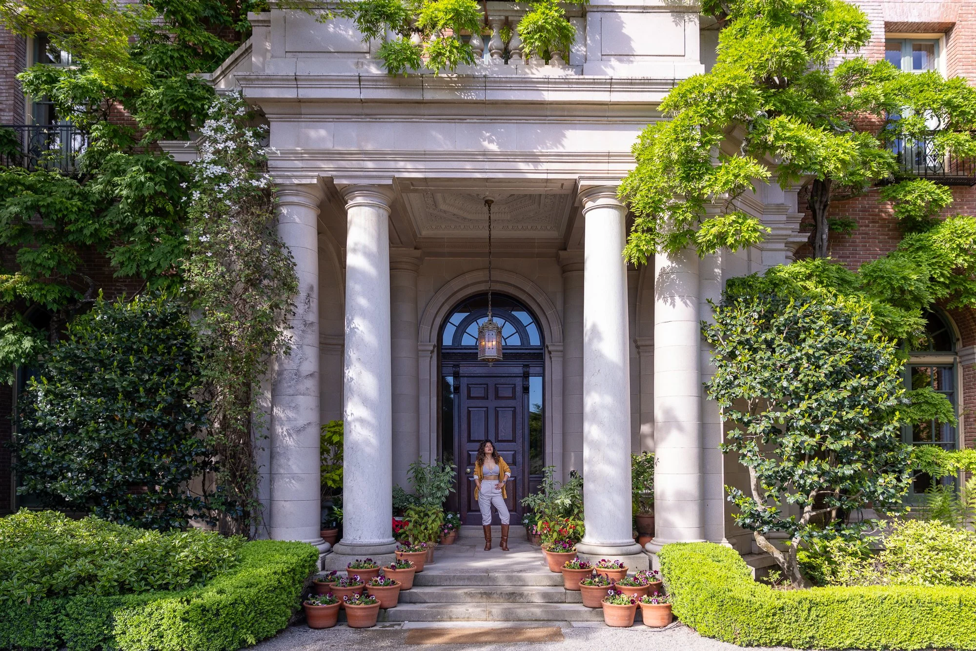 Woman in mustard outfit standing at Filoli mansion entrance, formal columns and ivy-covered brick, Woodside Bay Area portrait