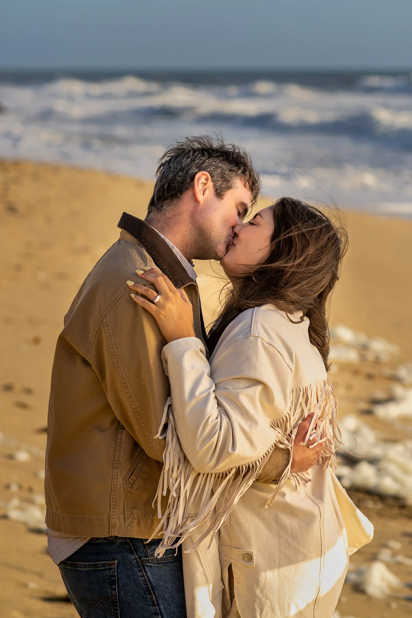 Engaged couple kissing on the beach at golden hour in Half Moon Bay