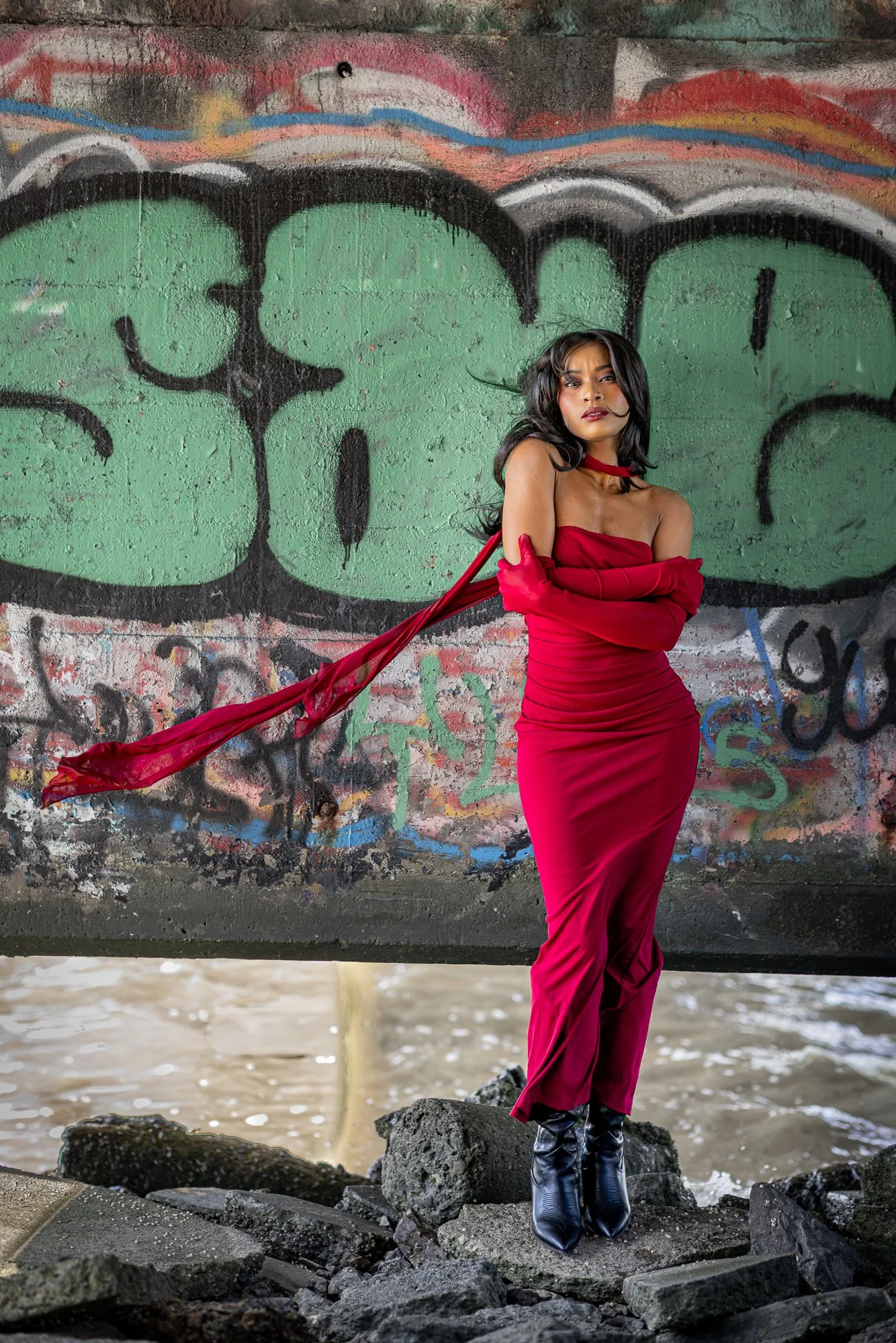 Woman in red gown and opera gloves on concrete rubble against graffiti wall, Dumbarton Shoreline Trail Newark, editorial portrait