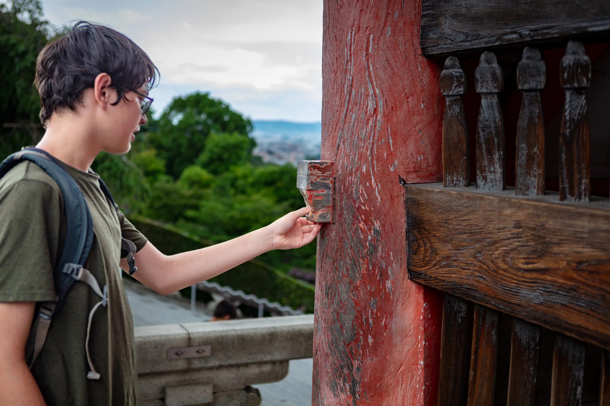 Teenager touching ancient red painted pillar Kiyomizudera Kyoto Japan