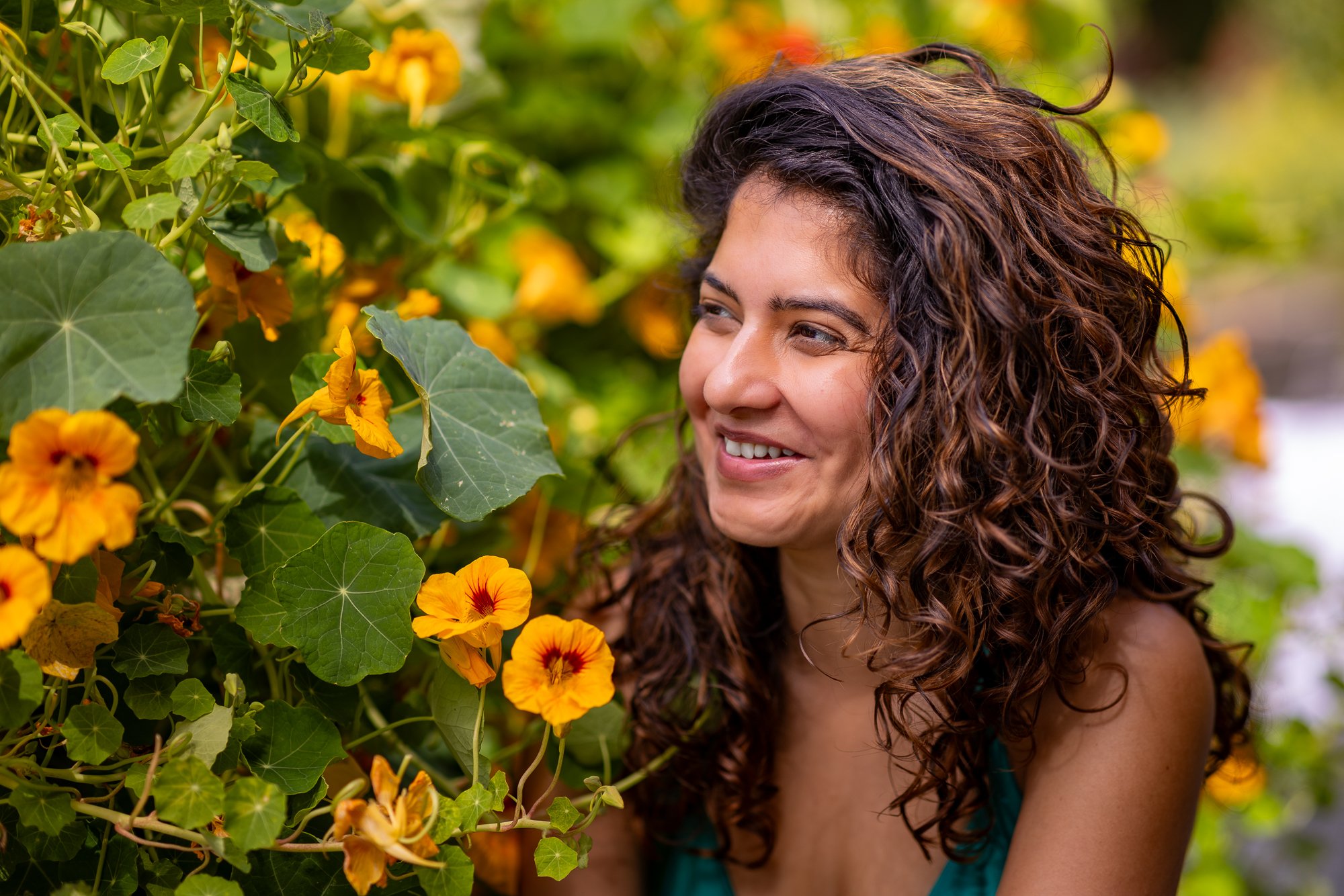 Woman laughing among orange nasturtium flowers at Filoli garden, candid natural light portrait Bay Area