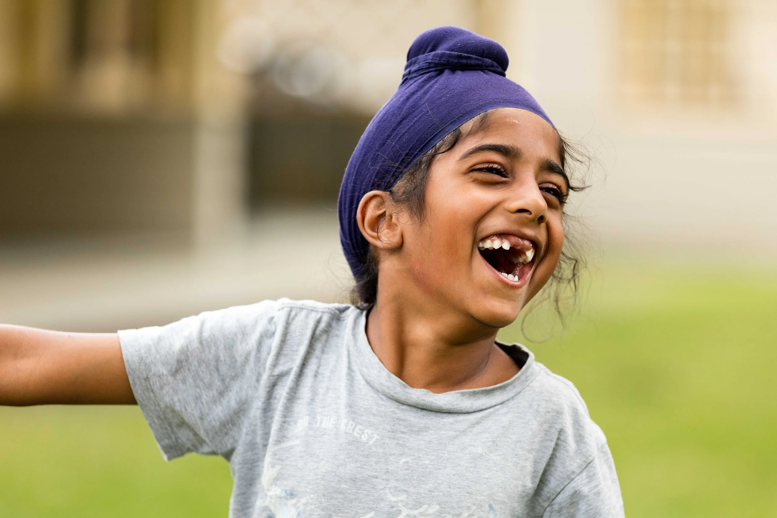 Mountain View family photography adventure session - A young girl with a big smile, wearing a purple headscarf and a gray T-shirt, enjoying outdoors.