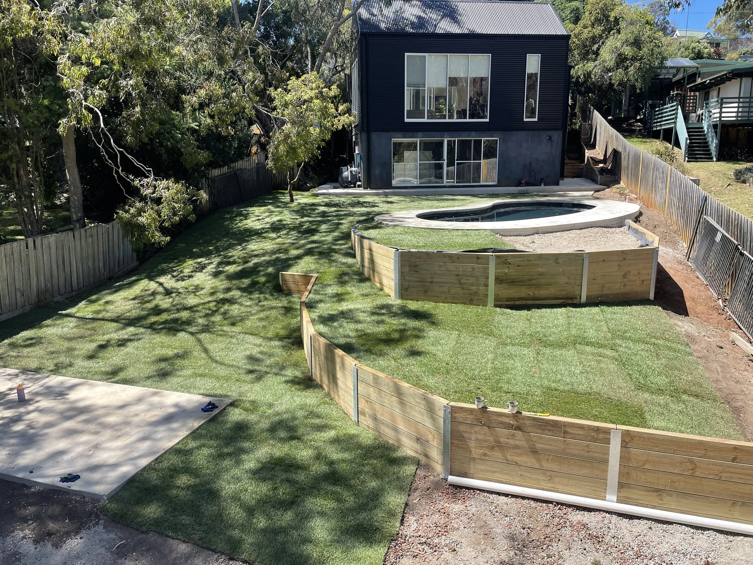 Rock salt finished concrete pool surrounds and shed slab with retaining walls and fresh turf all done by the Everstone team