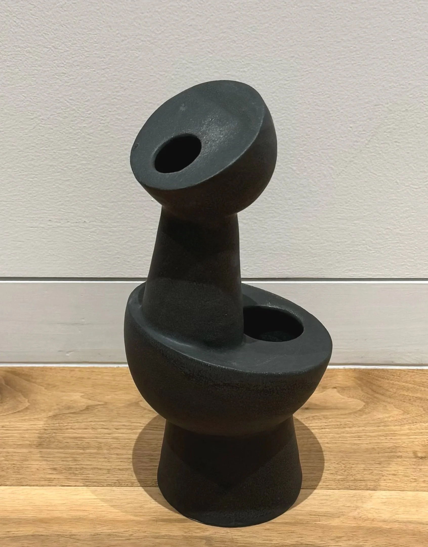 A black abstract asymmetric sculpture with a two holes that play with balance.