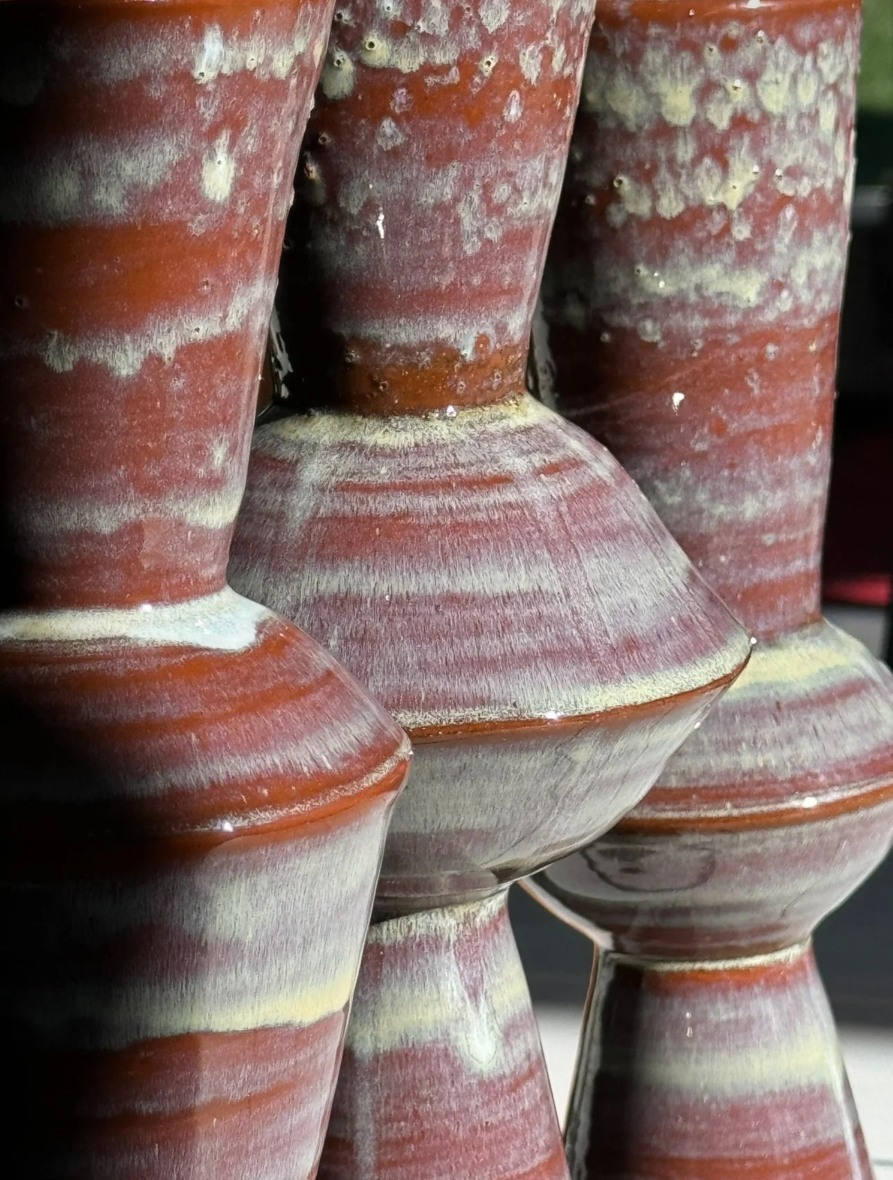 A close-up view of several pottery vases with a red and white striped pattern stacked together.