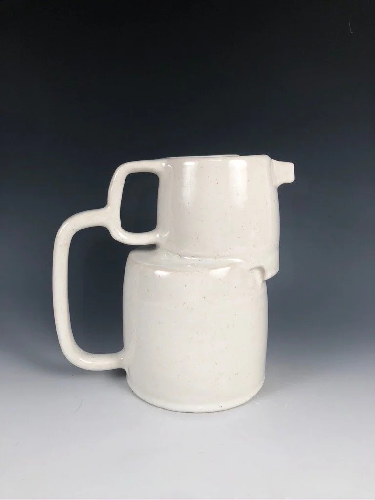 White asymmetric ceramic pitched with two stacked forms and two handles with a spout.