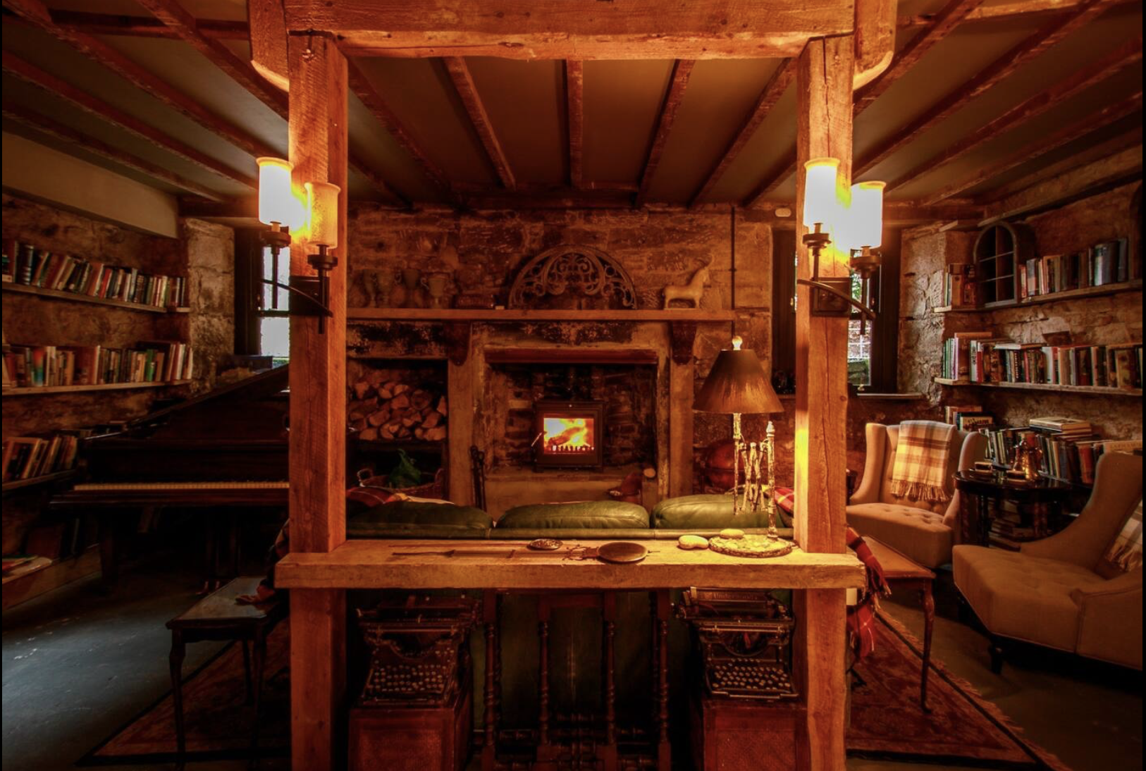 Cozy living room with brick walls, a fireplace, bookshelves, a piano, and seating area.