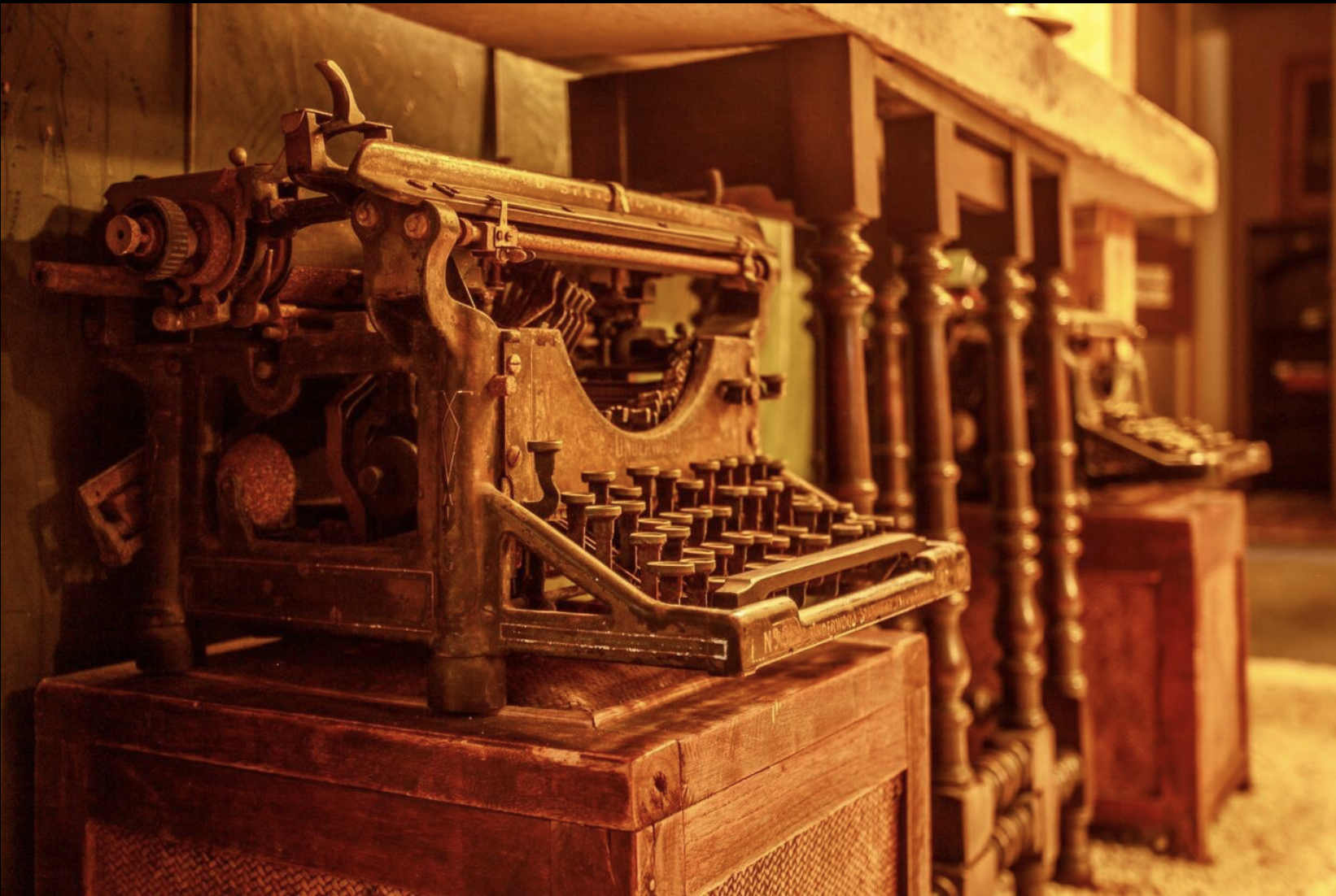 Vintage typewriter on a wooden table, in a room with antique furniture and warm lighting.