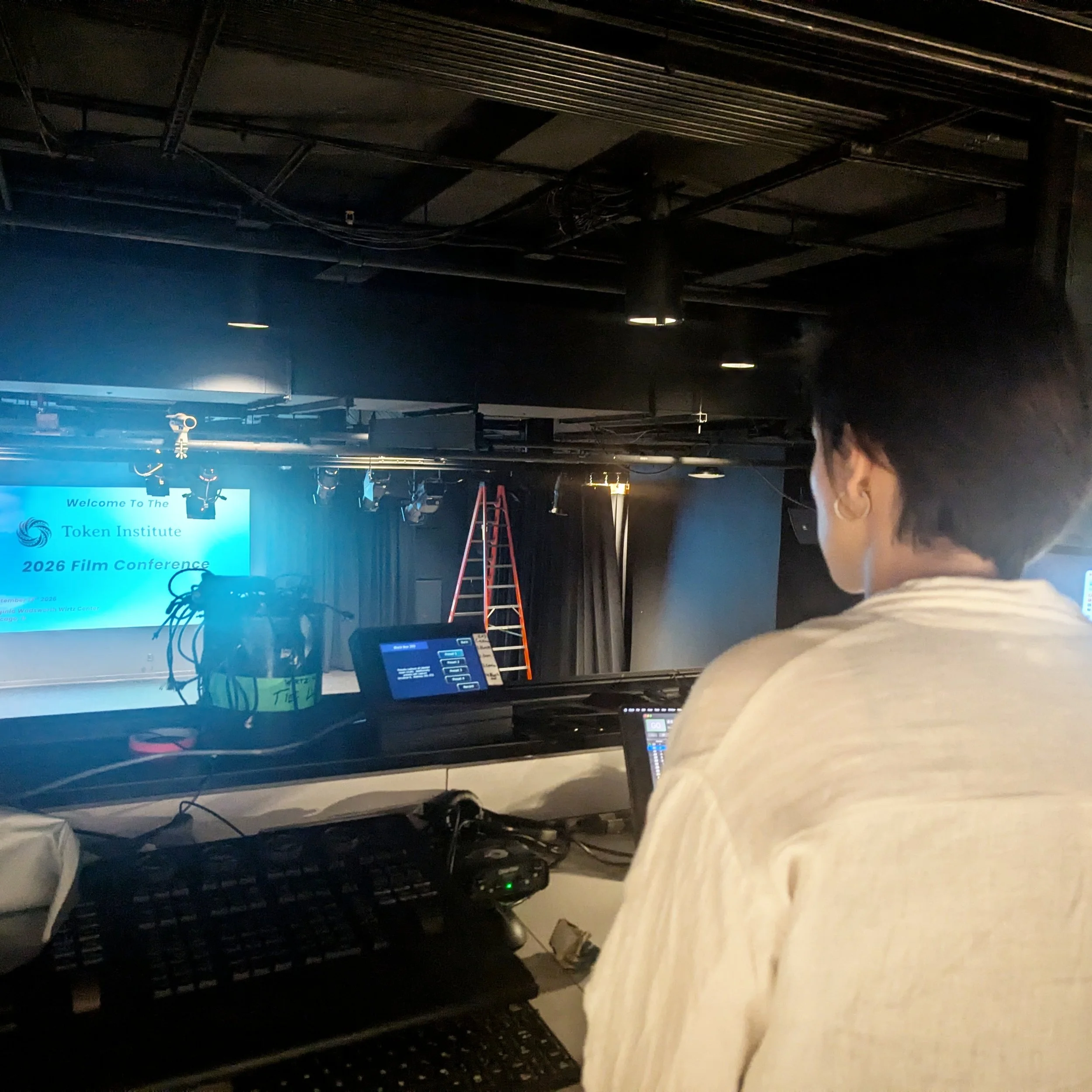 A lot of work goes into hosting a film conference that's often invisible. Pictured here is a behind the scenes action photo of our incredible projectionist Hayd&eacute;e preparing for the conference in the booth!