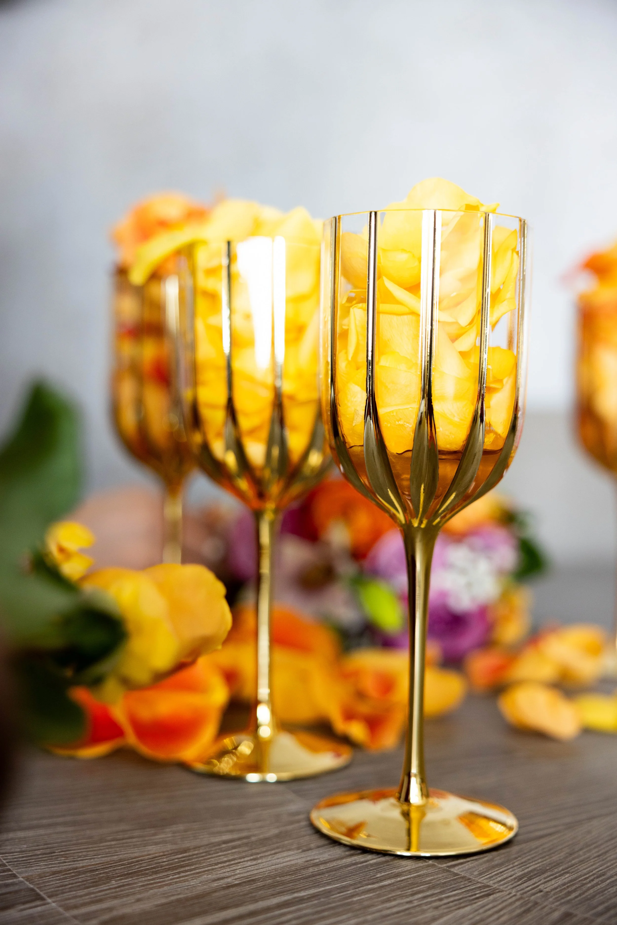 Clear glasses with golden stripes on a table with orange flowers over flowing