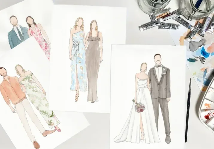 Fashion sketches and watercolor paintings of wedding and formal wear on a white table, with art supplies nearby.