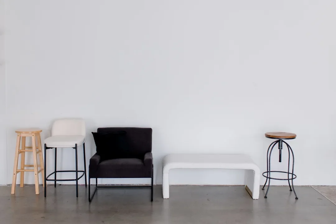 Row of five different stools and chairs against a plain white wall.